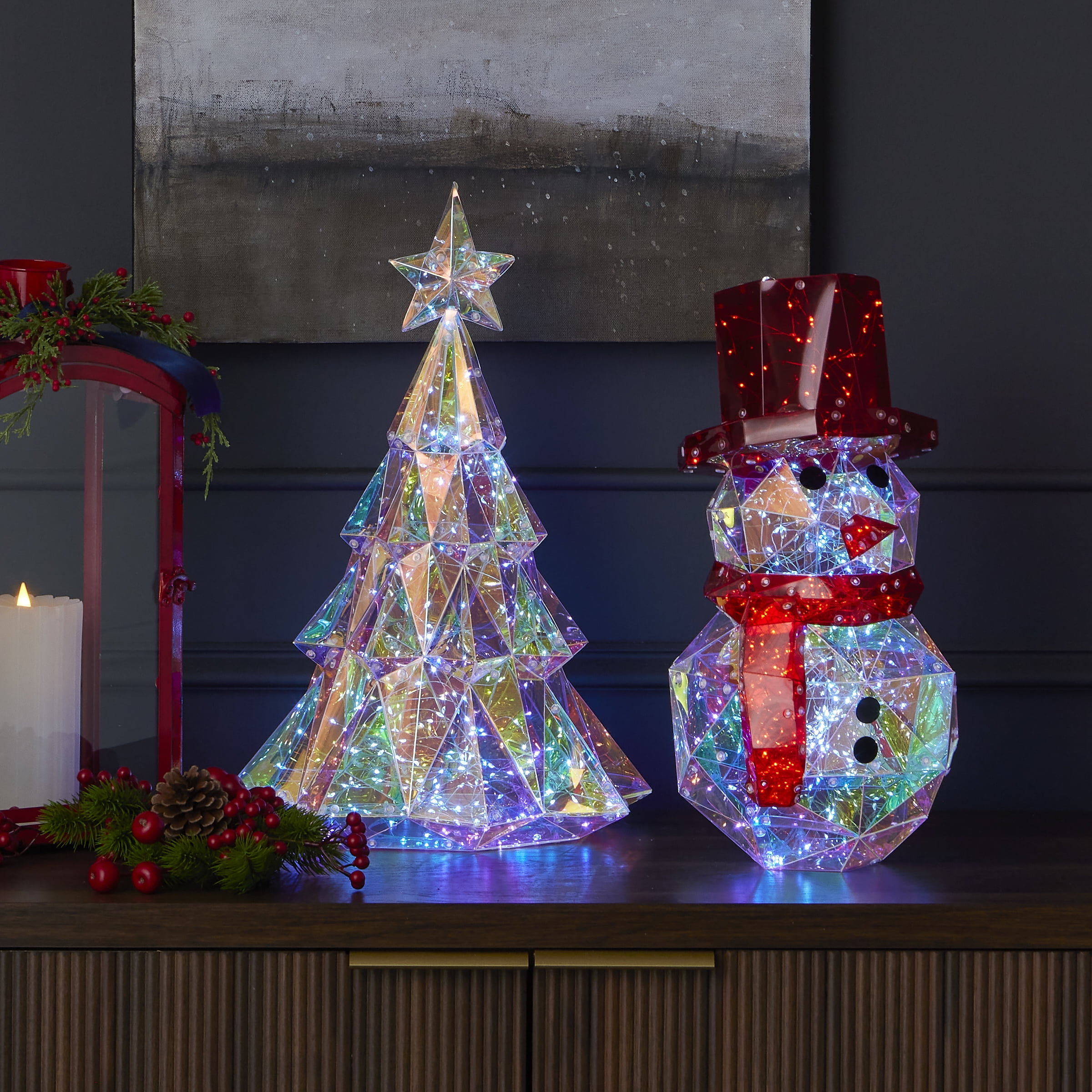 Weihnachtsdekorationen: beleuchteter Baum und Schneemann, roter Hut, Schal und Akzente. Auf Holzoberfläche mit Schrank.
