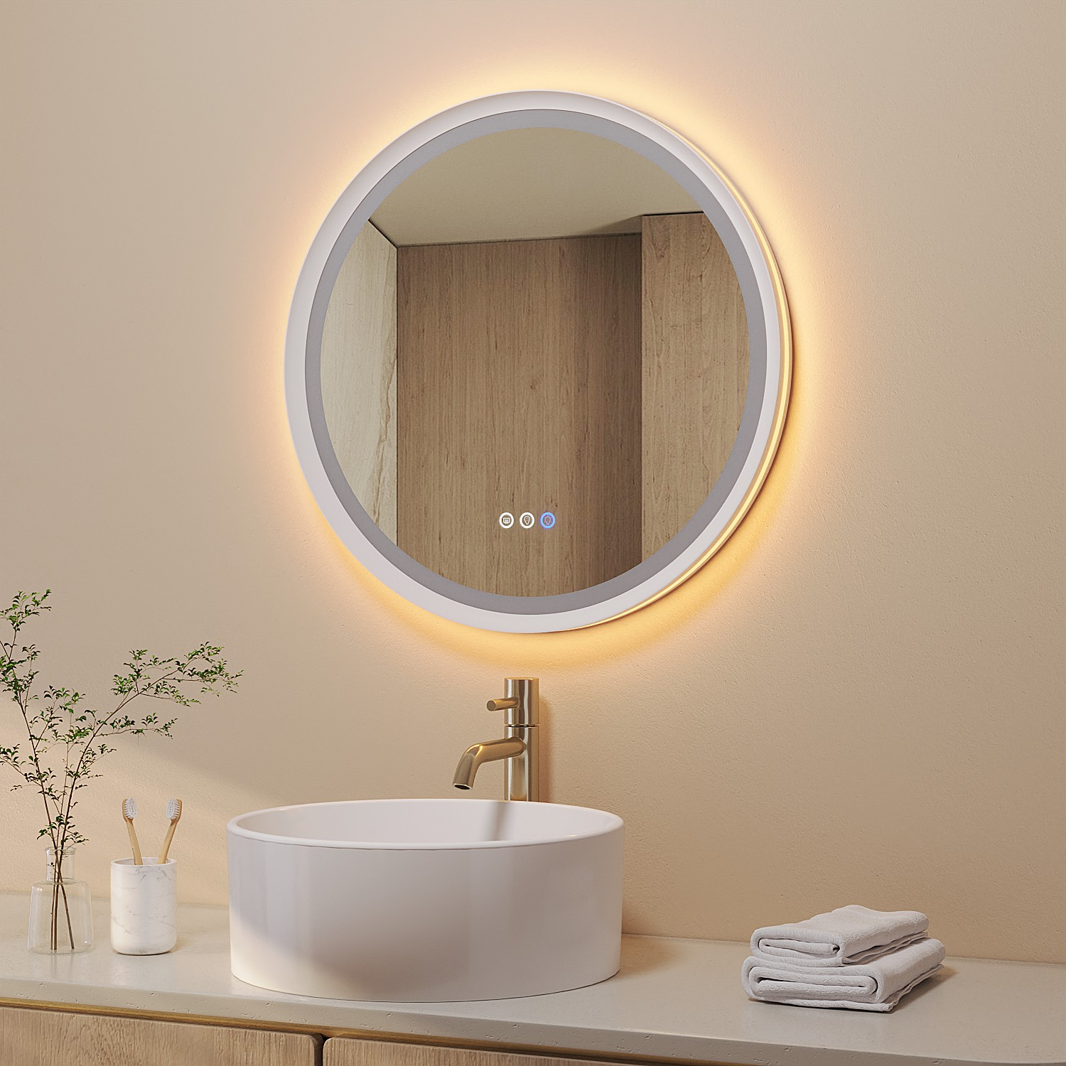 Ein modernes Badezimmer mit rundem beleuchteten Spiegel, weißem Waschbecken und goldener Armatur. Handtücher und Pflanzen.