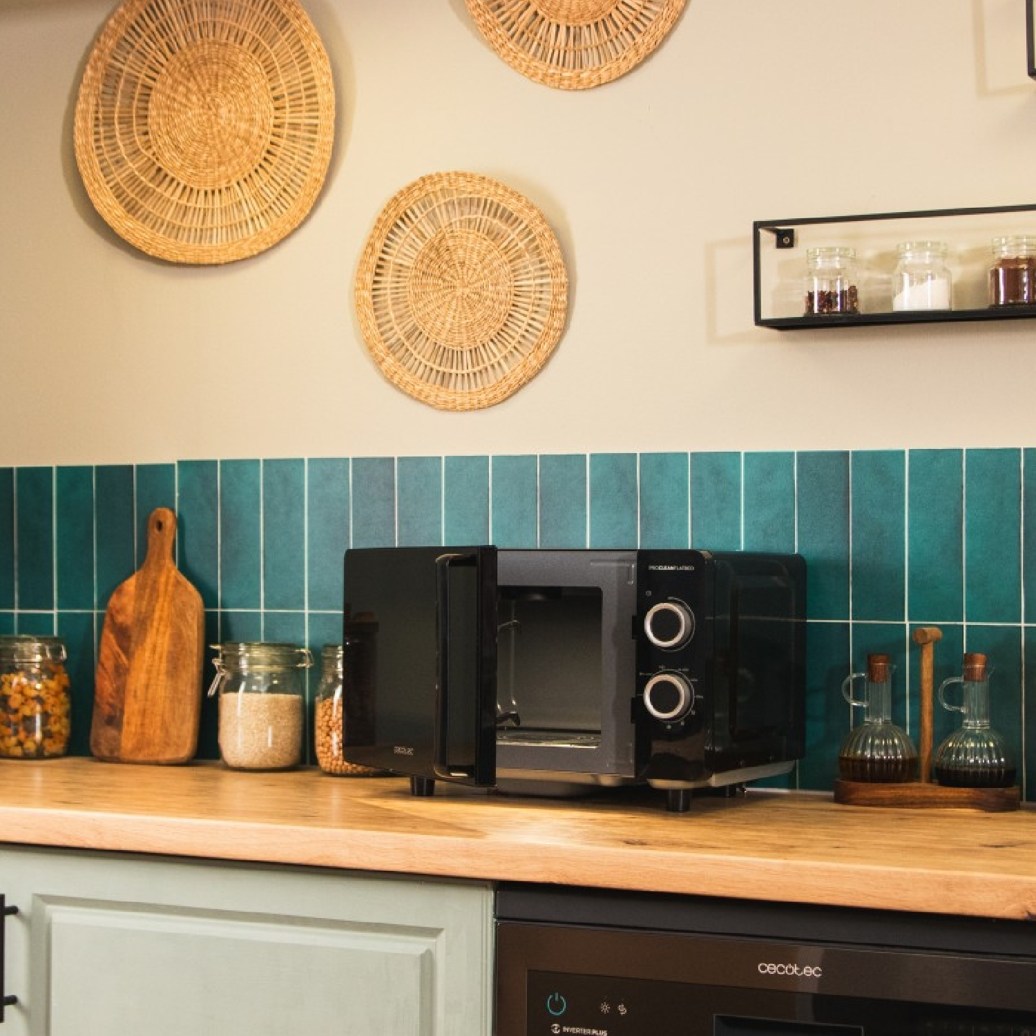 Scena cucina con microonde nero aperto. Vasi, tagliere e cesti intrecciati decorano lo spazio. Piastrelle verdi sullo sfondo.