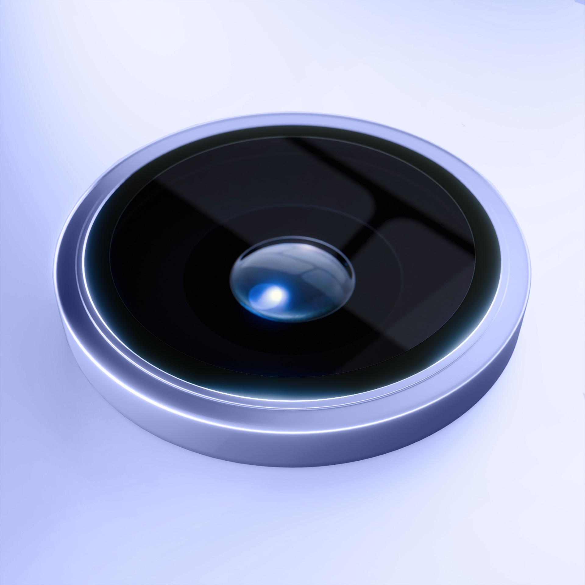 Primo piano dell'obiettivo di una fotocamera del telefono. L'obiettivo è nero, circondato da un anello argentato, su sfondo azzurro.