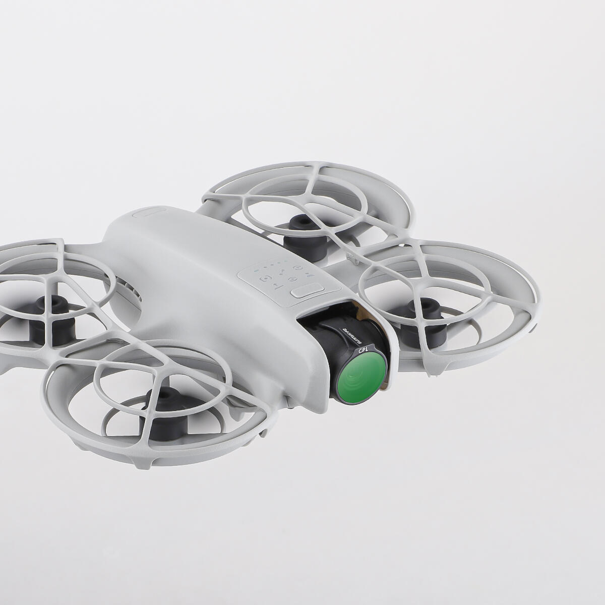 A gray drone with four propellers is shown against a white background. The drone has a camera with a green lens.
