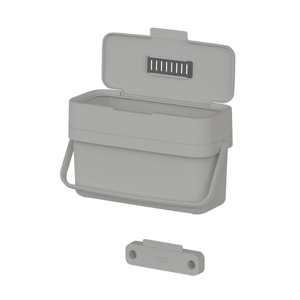 Un cubo de compostaje gris con tapa abierta, asa y una pieza magnética gris separada con dos agujeros.