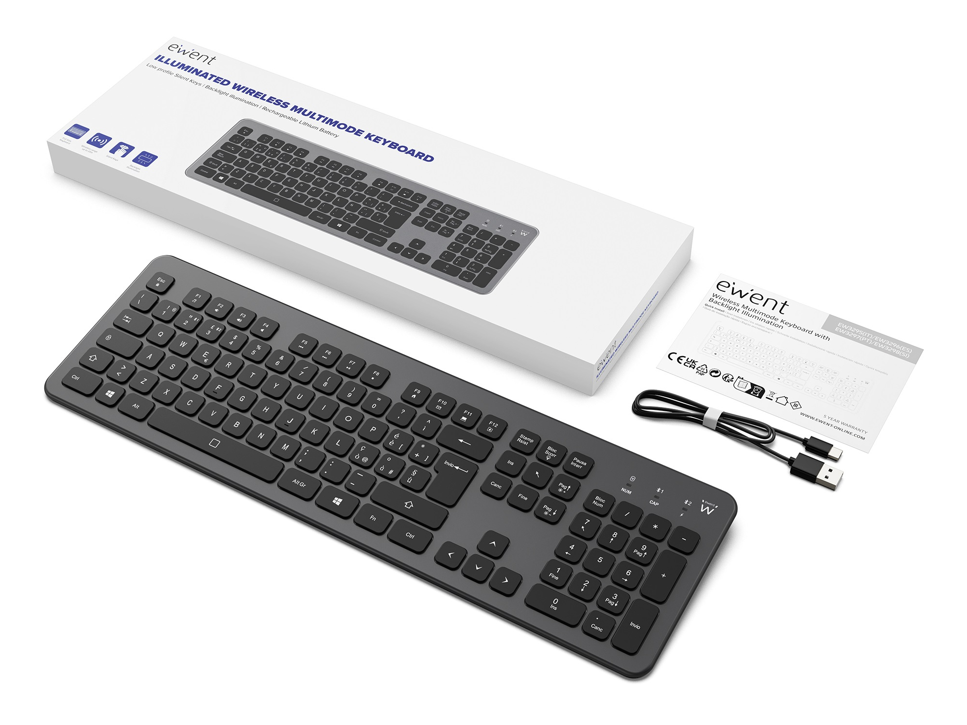 Una tastiera wireless nera, parzialmente fuori dalla sua scatola, con cavo di ricarica e documentazione su una superficie bianca.