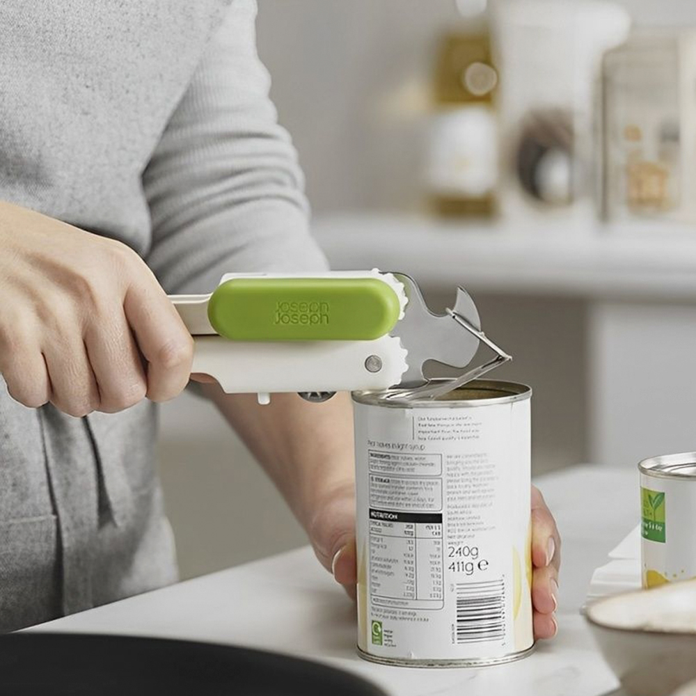 Una persona usa un abrelatas para abrir una lata de comida. El abrelatas es blanco y verde. El fondo es una cocina.