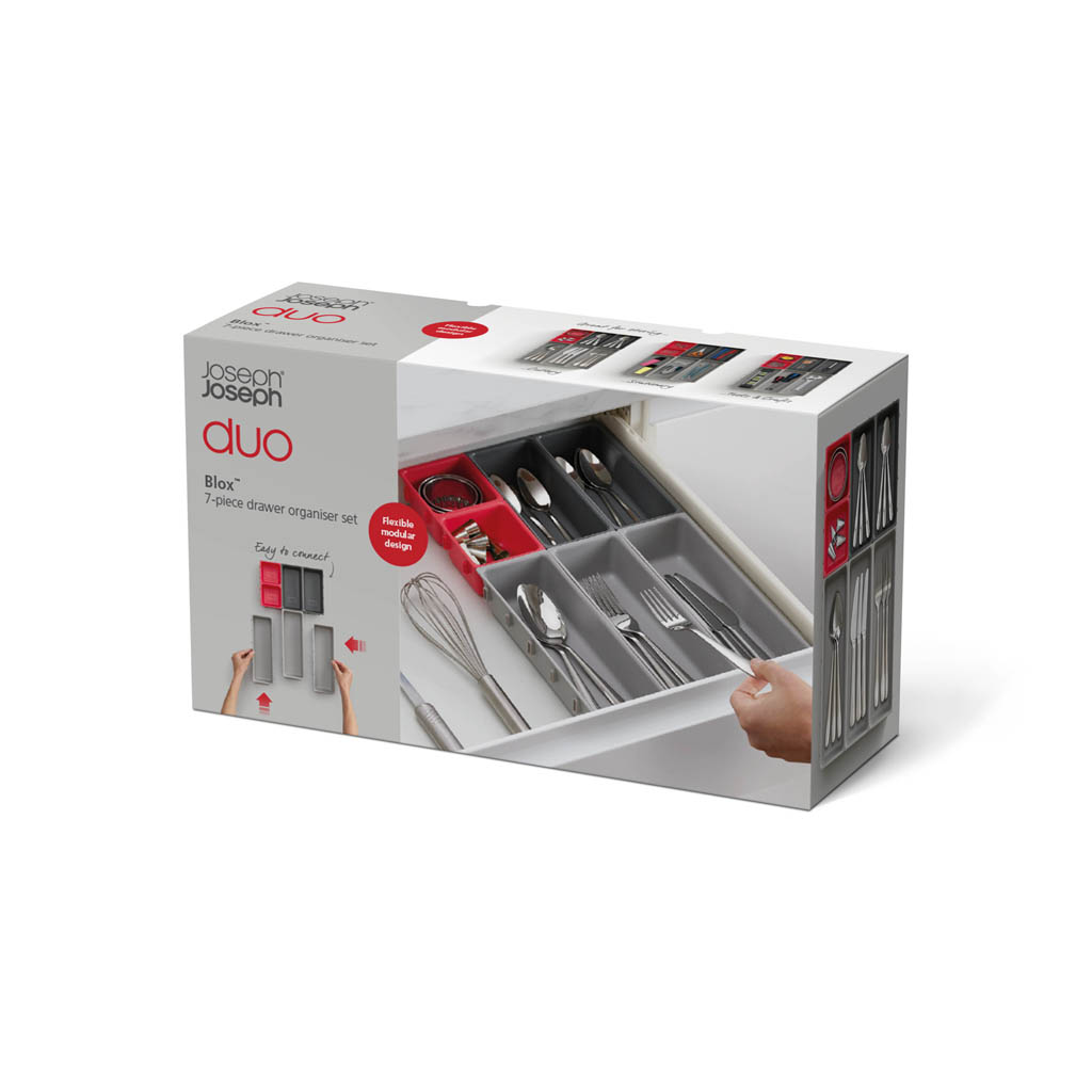 Una caja muestra un juego organizador de cajones, con cubiertos y utensilios de cocina. Es un juego Joseph Joseph Duo Blox de 7 piezas.