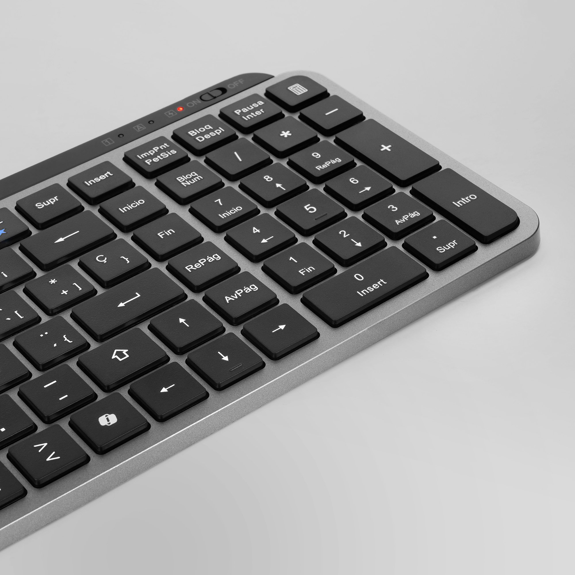 Primer plano de un teclado plateado con teclas negras. Las teclas incluyen números, flechas y teclas de función.