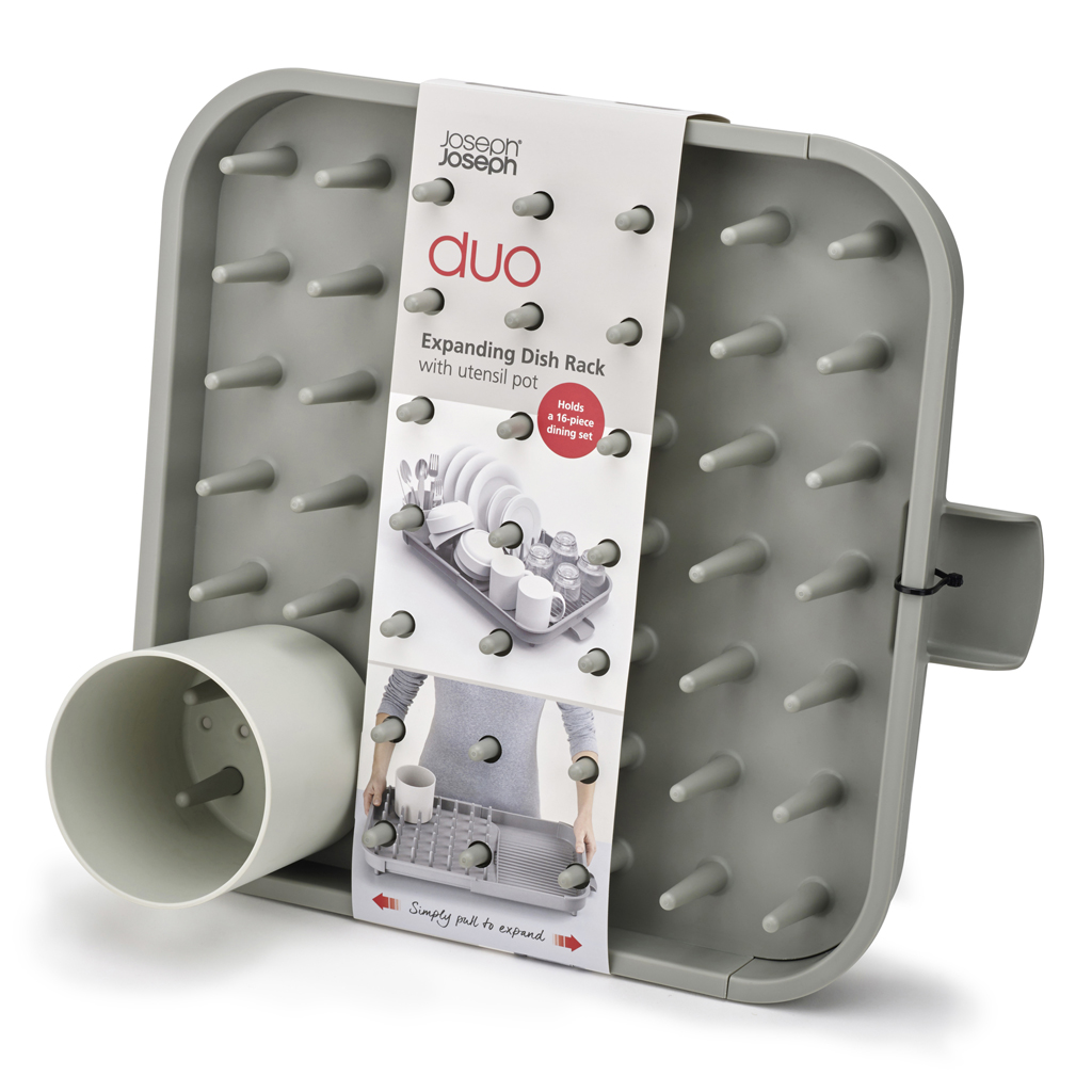 Un escurreplatos gris con clavijas y un recipiente para utensilios. Una etiqueta muestra un juego de comedor. Es un escurreplatos extensible.