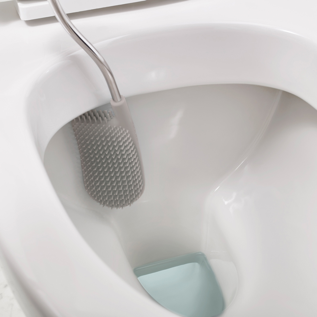 Primer plano de un inodoro blanco. Hay un cepillo de inodoro gris dentro. Es visible un deflector de agua azul claro.