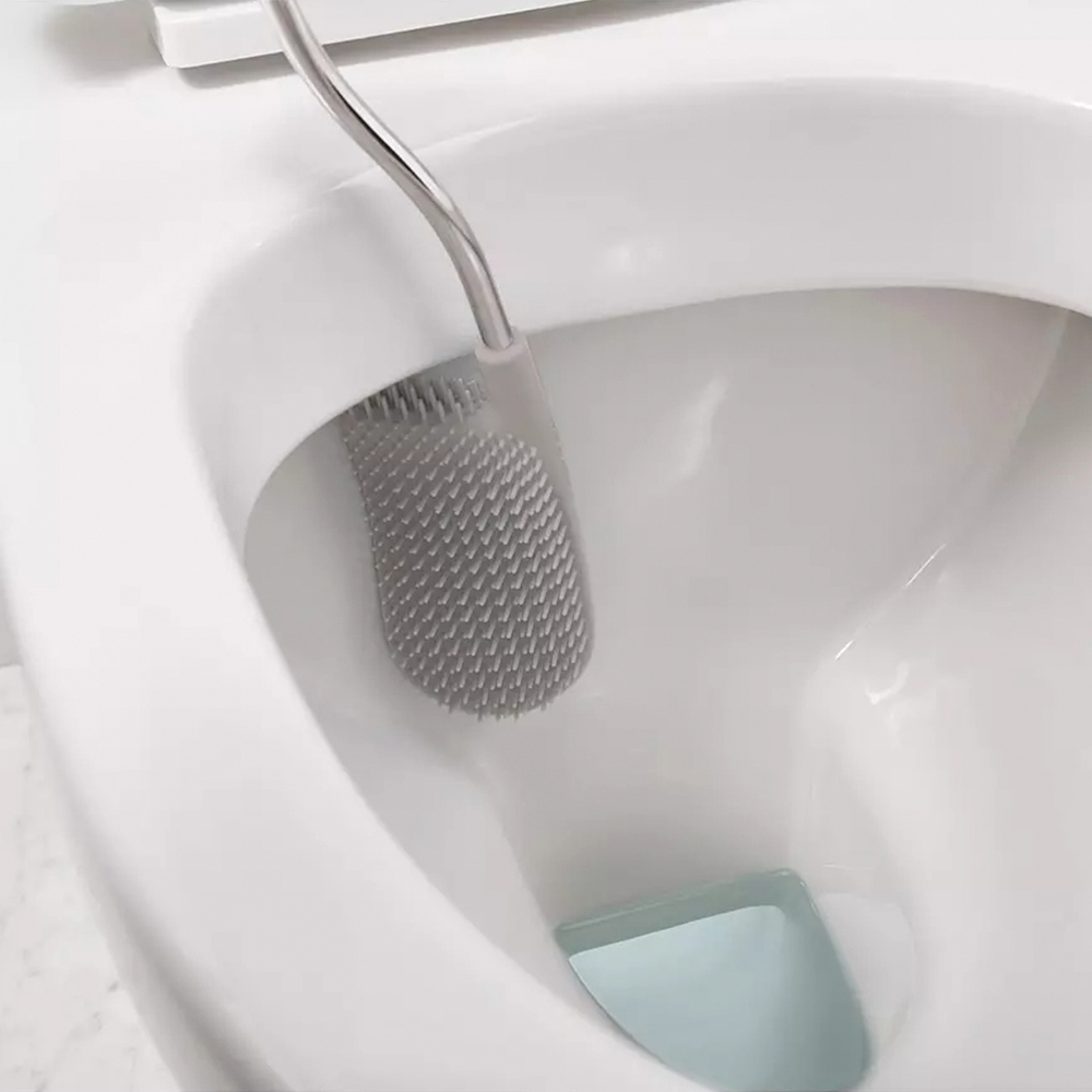 Un inodoro con un cepillo de inodoro gris dentro. El inodoro es blanco. El cepillo es de silicona.