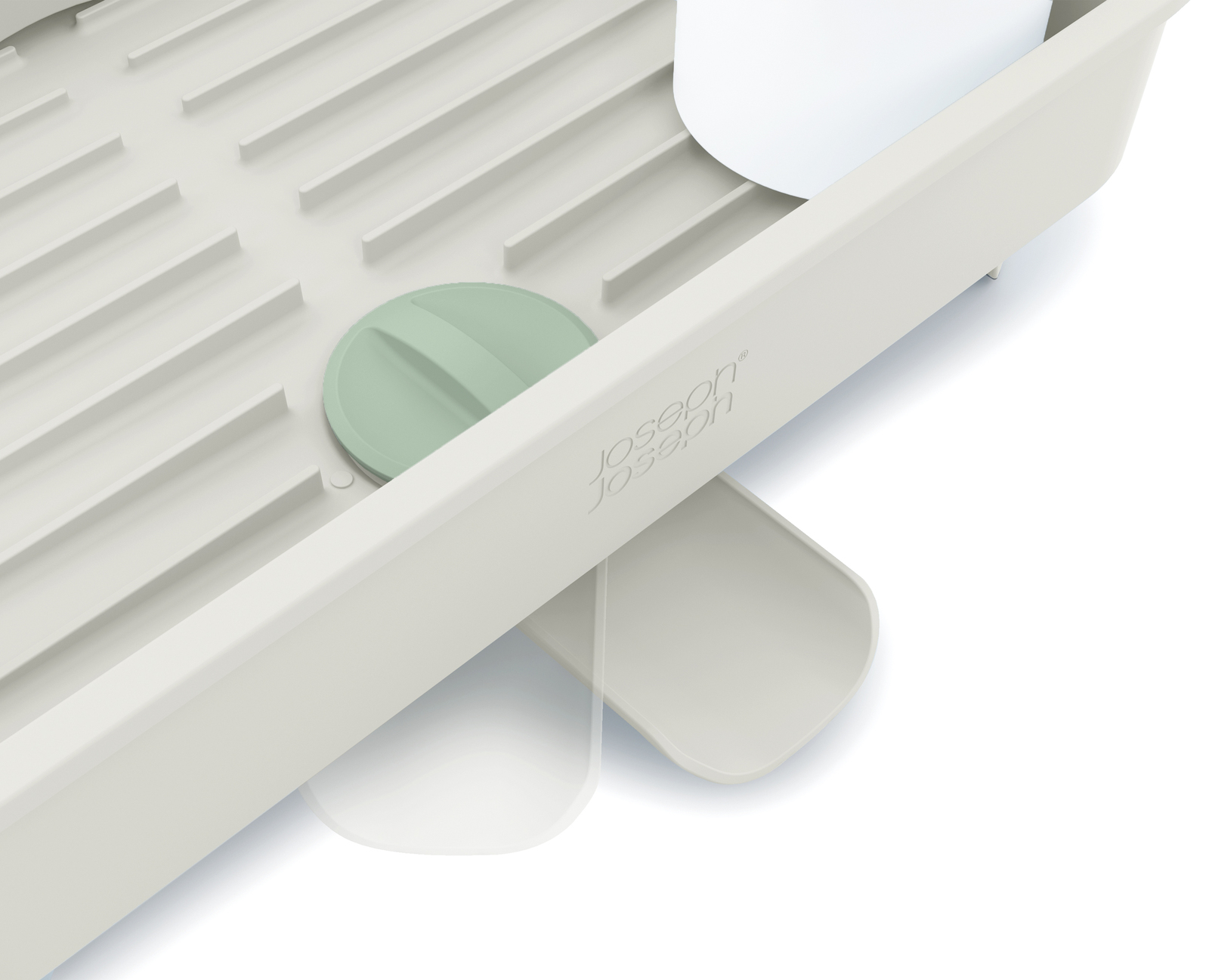 Primer plano de un escurreplatos beige con tapa verde, taza blanca y el logotipo de Joseph Joseph.