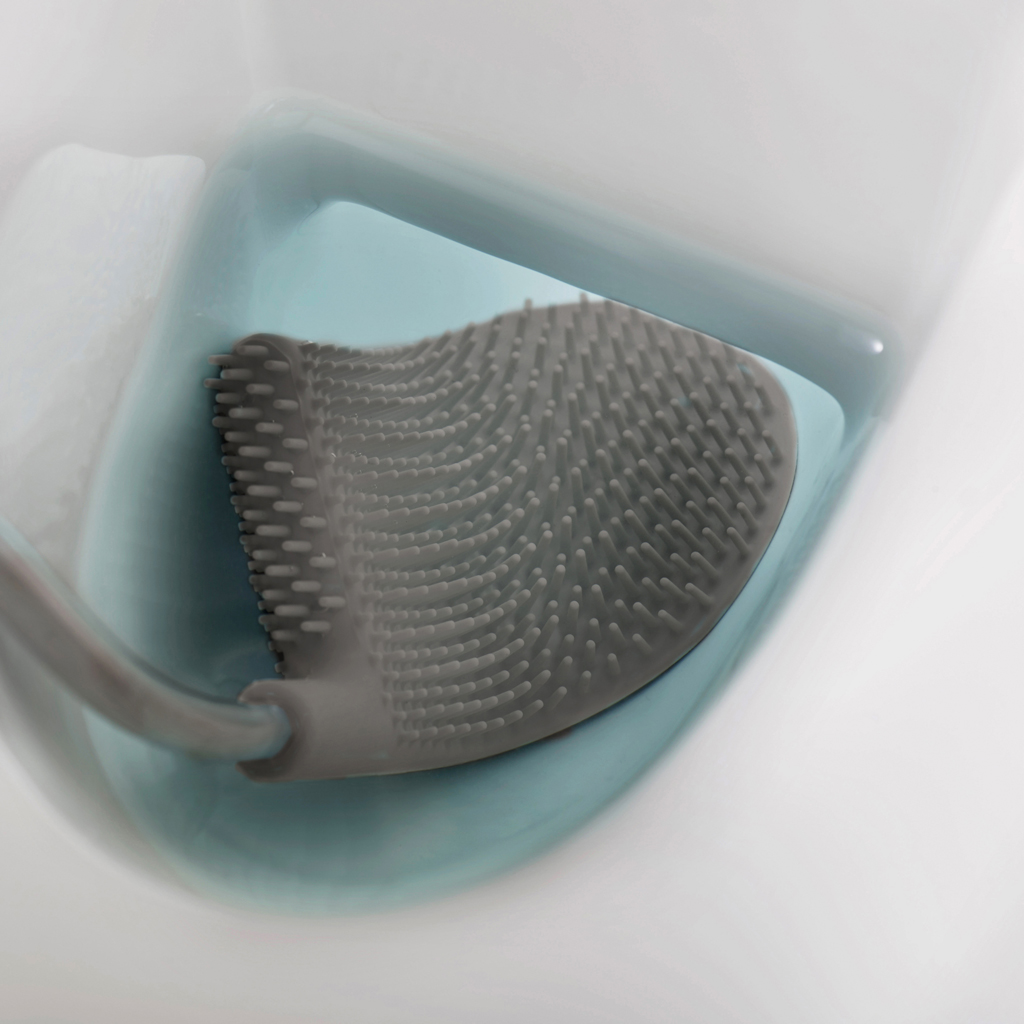 Un cepillo de inodoro gris con cabezal de silicona está en un inodoro azul. El inodoro está dentro de un inodoro blanco.