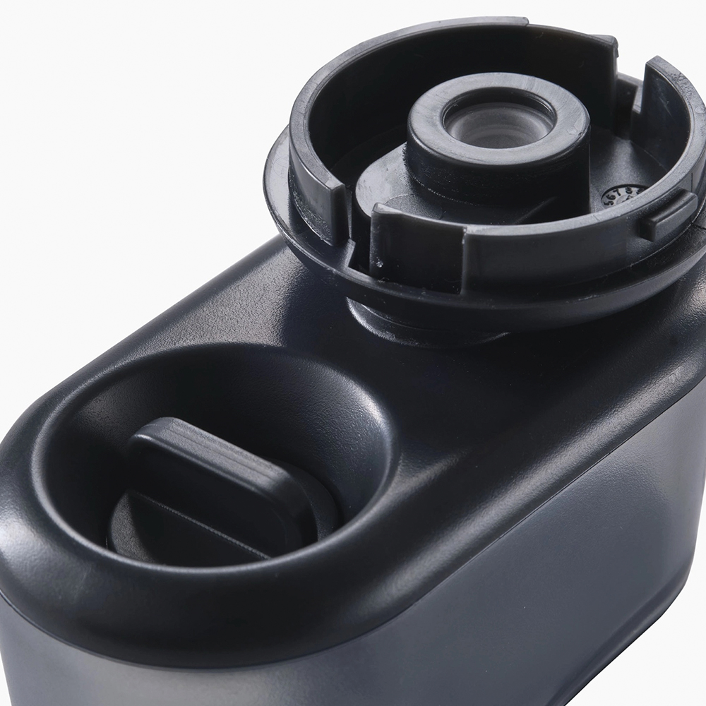 Primer plano de un dispositivo de plástico gris oscuro. Tiene una parte superior circular con un agujero y una base redondeada con un botón rectangular más pequeño.