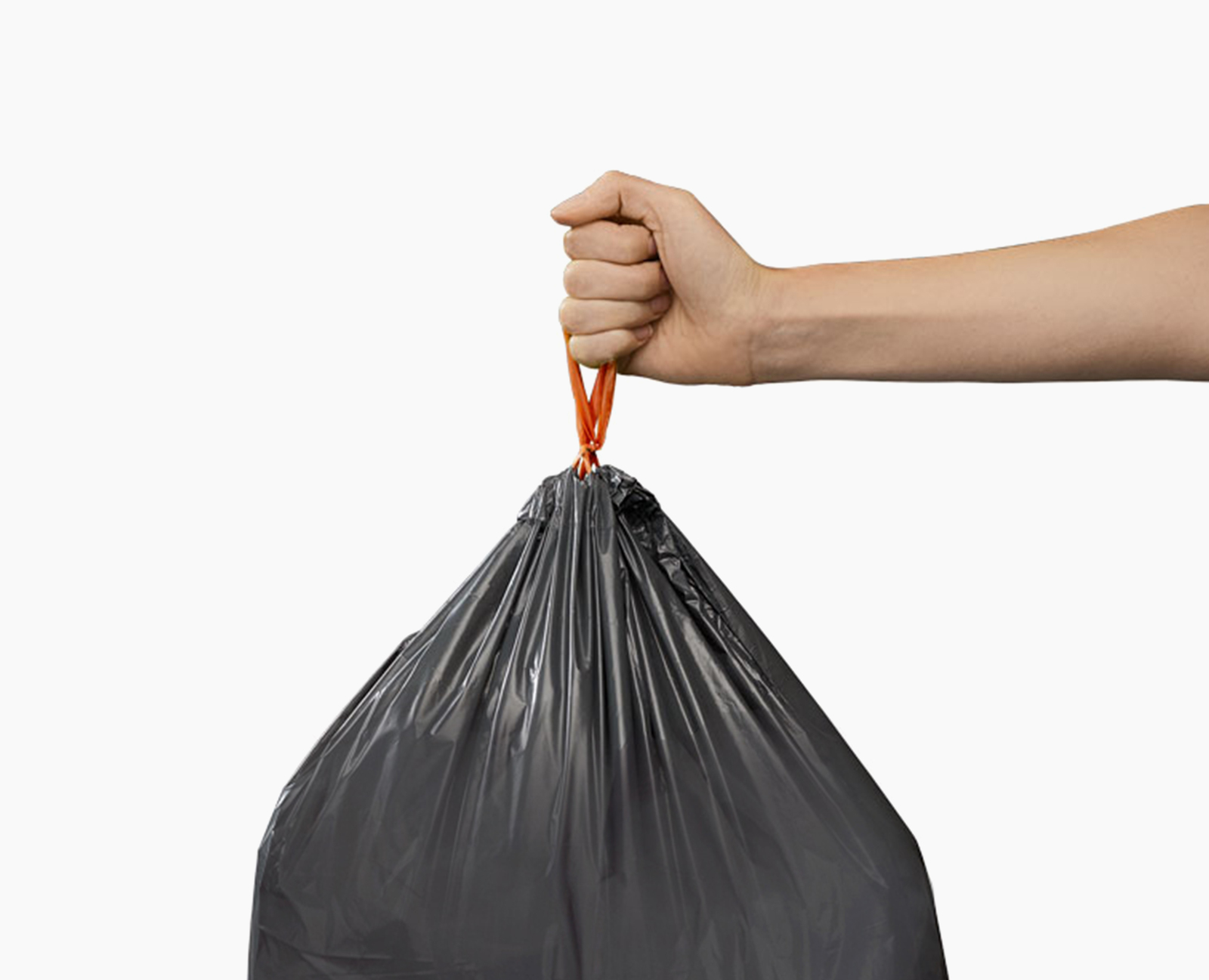 Una mano sostiene una bolsa de basura negra por su lazo naranja. La bolsa está llena y sobre un fondo blanco.