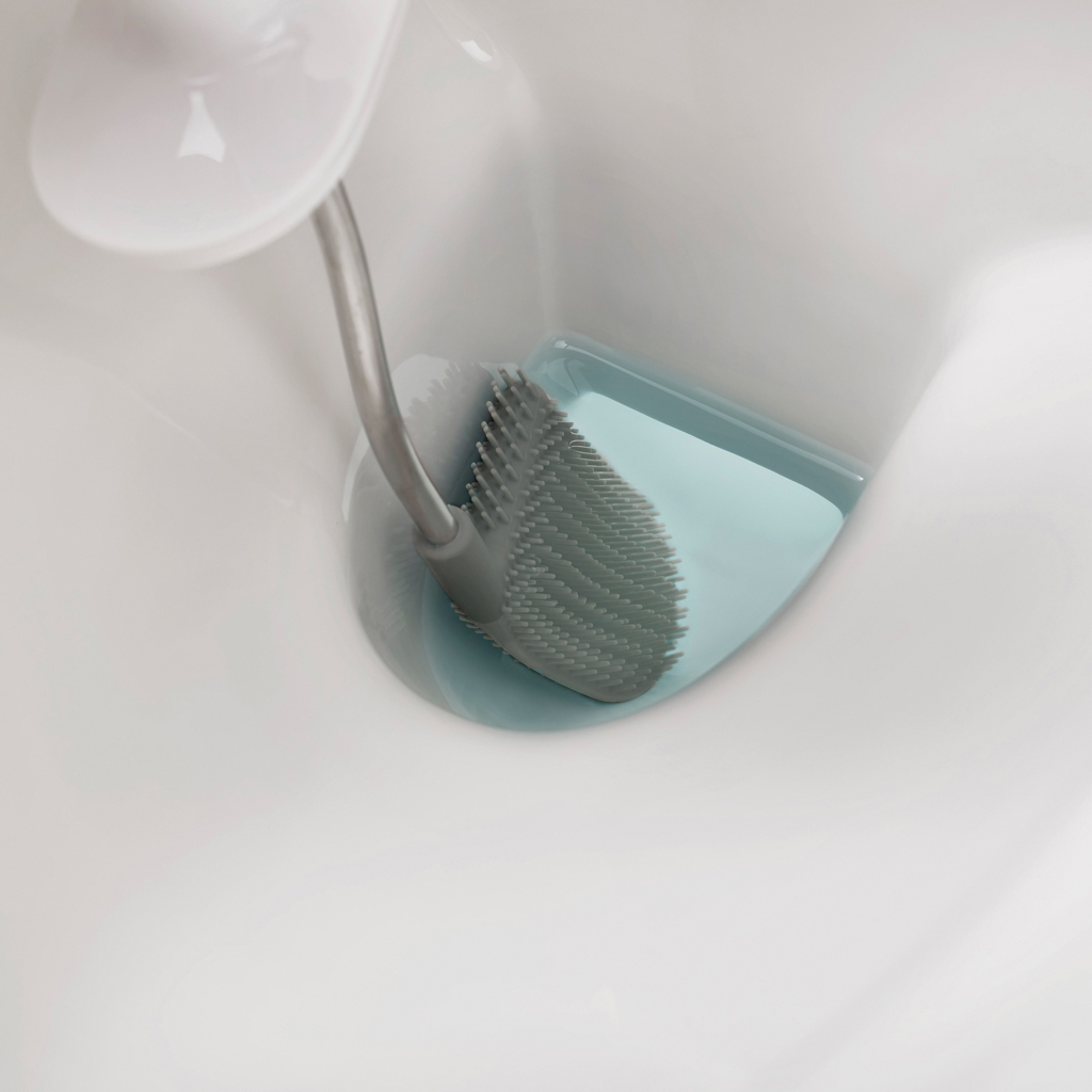 Un cepillo de inodoro en un soporte. El cepillo es gris y el soporte es azul claro. El fondo es blanco.