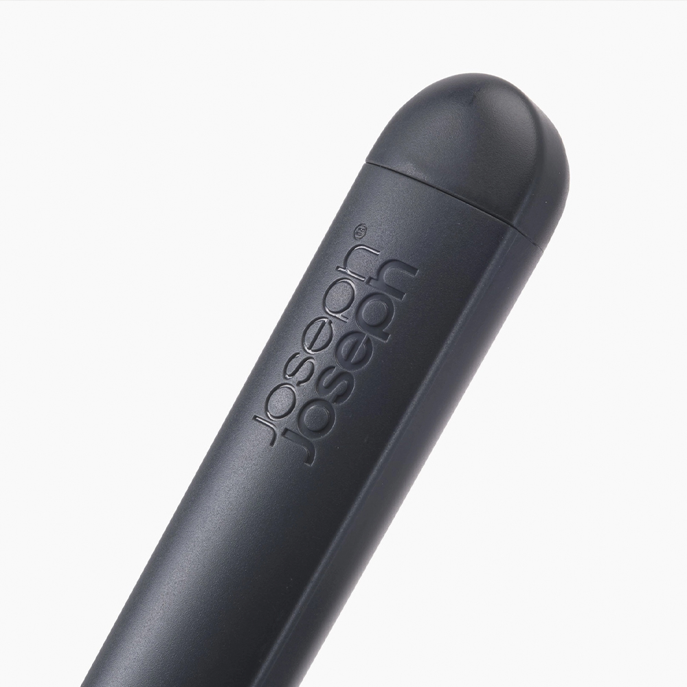 Primer plano de un utensilio de cocina gris oscuro. La marca 'Joseph Joseph' está grabada en el lateral. El fondo es blanco.