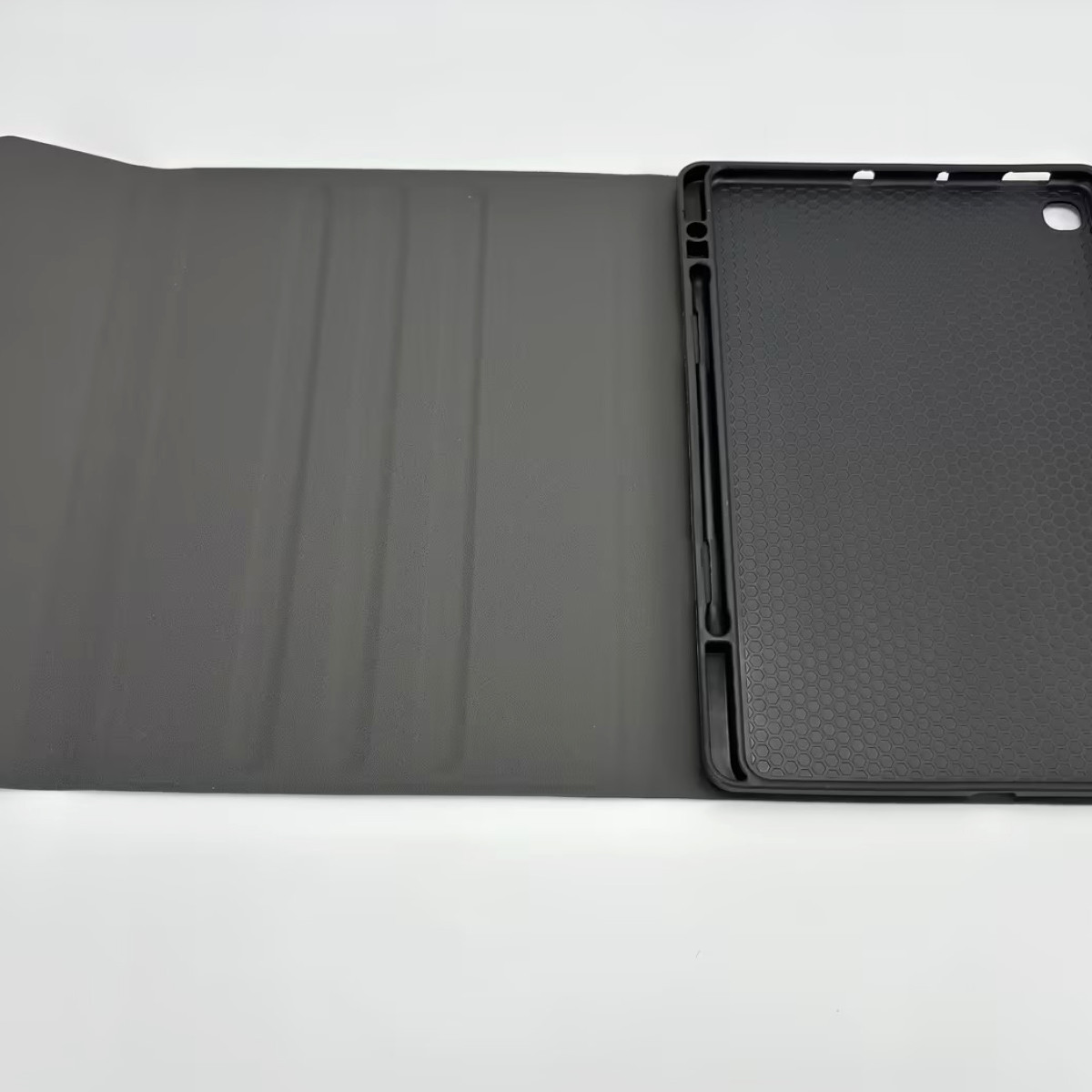 Czarne etui na tablet, otwarte na białej powierzchni. Prawa strona pokazuje wnętrze z wzorem plastra miodu. Lewa strona to pokrywa.