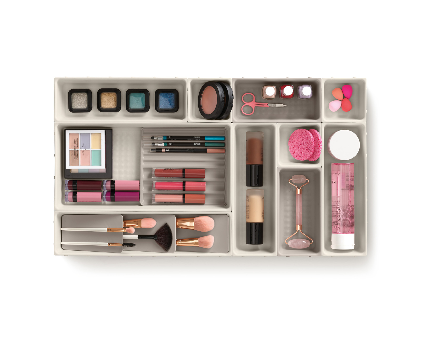 Organizador de maquillaje con sombras de ojos, labiales, brochas, bases, esponjas y un rodillo facial. Colores y formas variados.