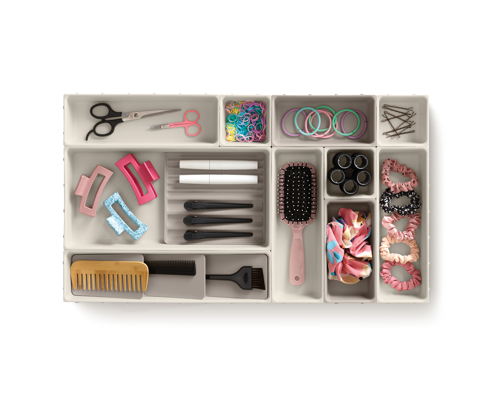 Organizador de cajones lleno de accesorios para el cabello, incluyendo tijeras, clips, gomas para el pelo, peines y un cepillo.