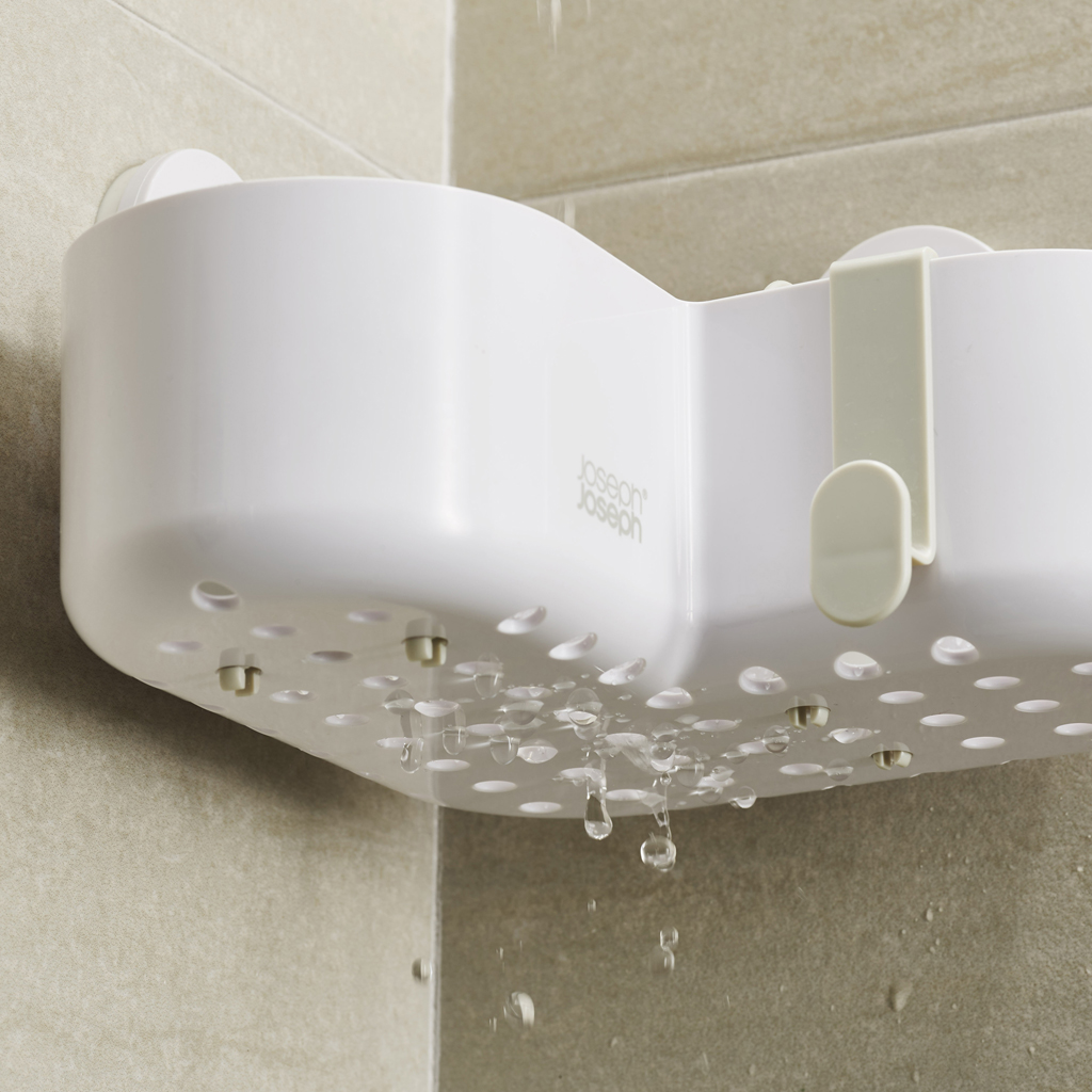 Estante de ducha blanco con gotas de agua. El estante está en una esquina, montado en una pared de azulejos.
