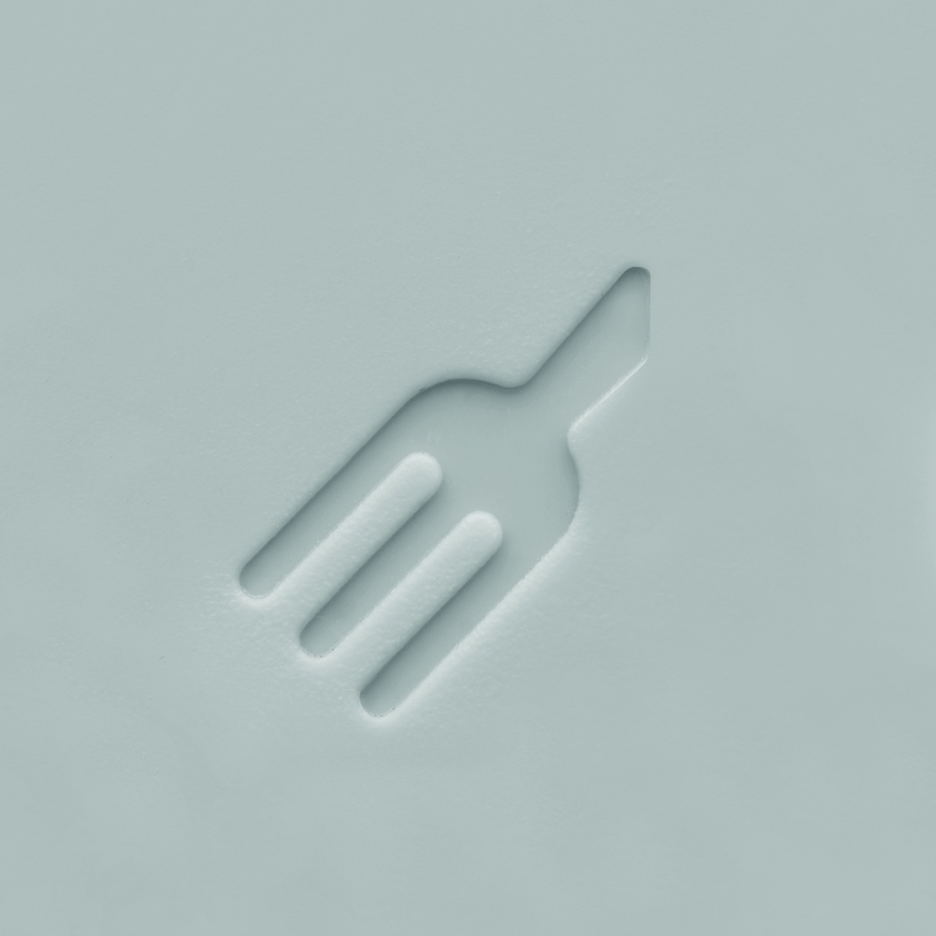 Un icono de tenedor blanco tallado en una superficie blanca. El tenedor tiene tres púas y un mango, todos delineados en el fondo blanco.