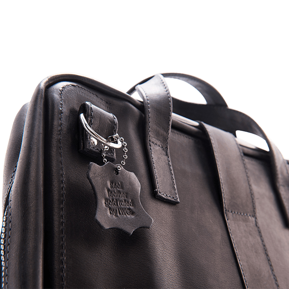 Primo piano di una borsa in pelle nera. Un'etichetta è appesa a un anello d'argento con la scritta 'Vera pelle con valutazione oro di LWG'.