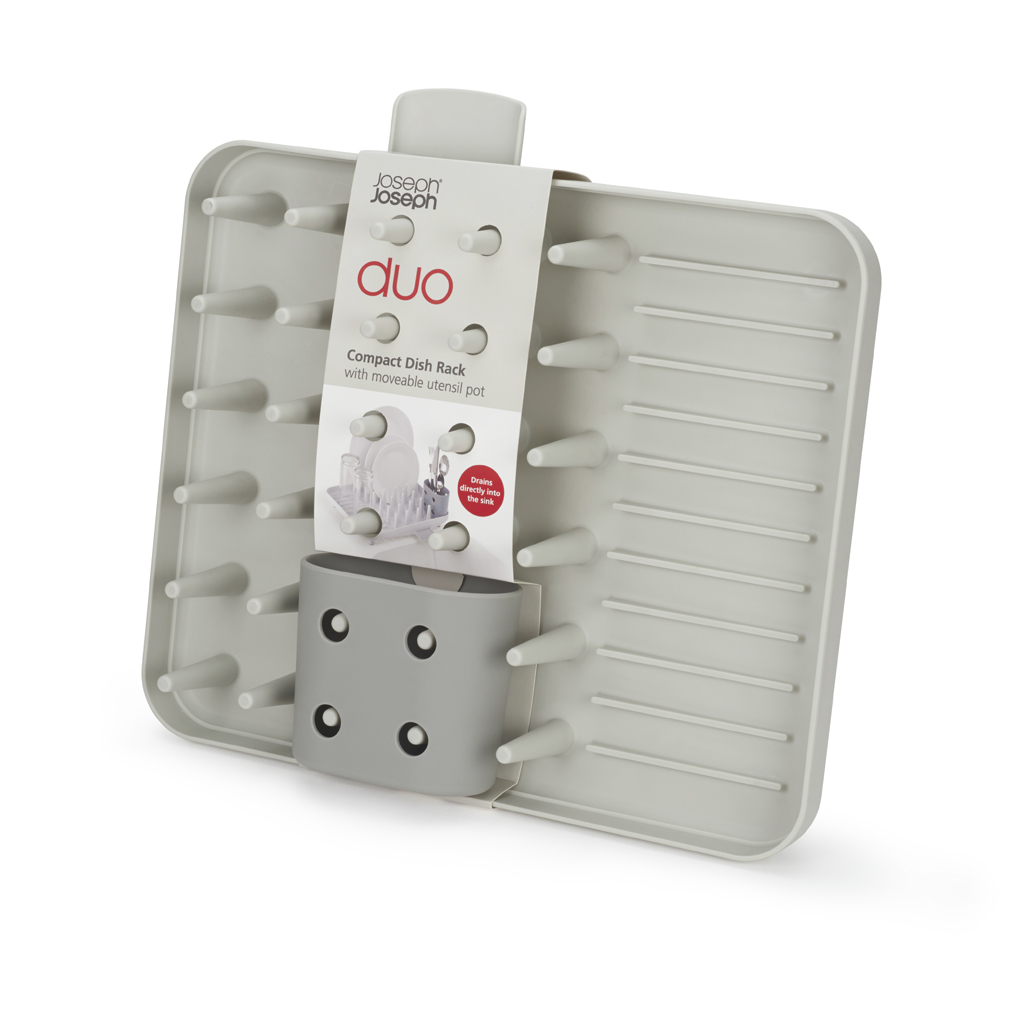Un scolapiatti compatto grigio con un portautensili e pioli. Ha un'etichetta con scritto 'Joseph Joseph duo Compact Dish Rack'.