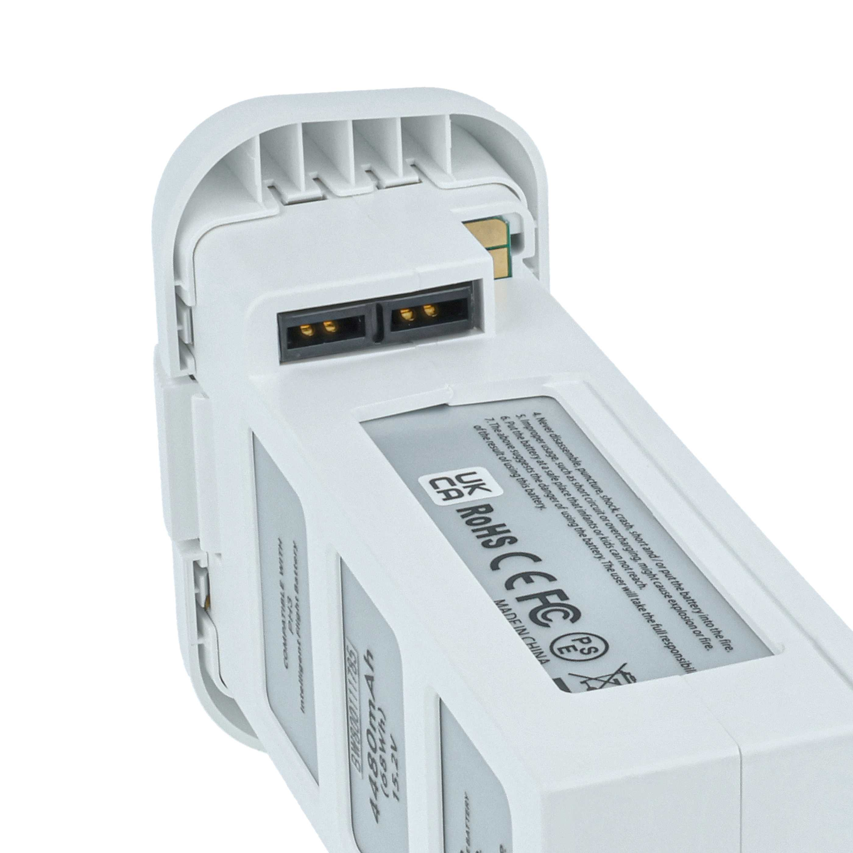 Eine weiße Drohnenbatterie wird gezeigt. Sie hat zwei schwarze Anschlüsse und ein Etikett mit Sicherheitshinweisen.