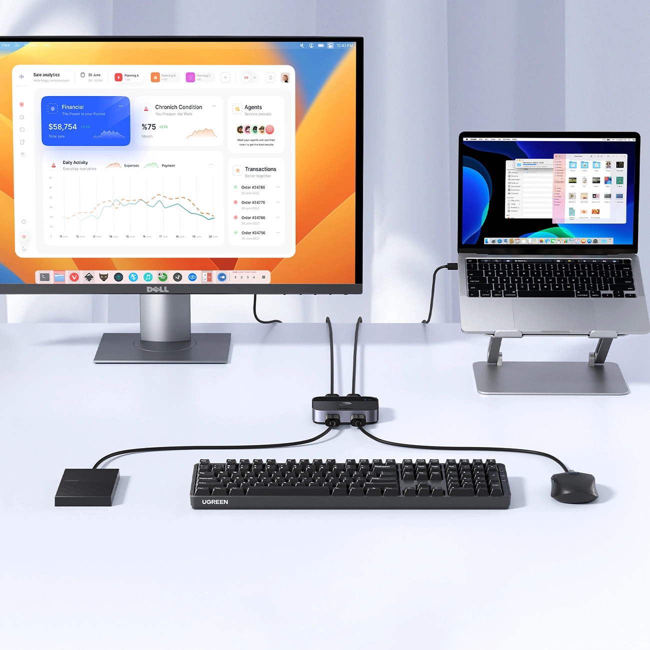 Konfiguracja z monitorem, laptopem na stojaku, klawiaturą, myszą i hubem, wszystko podłączone na białej powierzchni.