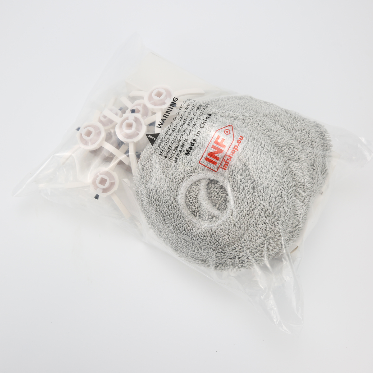 Przezroczysta plastikowa torba zawiera białe plastikowe dystanse i szarą podkładkę czyszczącą. Torba ma etykietę ostrzegawczą i czerwone logo.