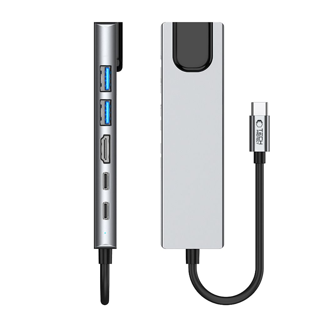 Een zilveren USB-C hub met meerdere poorten. Het heeft twee USB-poorten, een HDMI-poort en een USB-C-poort. Een zwarte kabel is aangesloten.