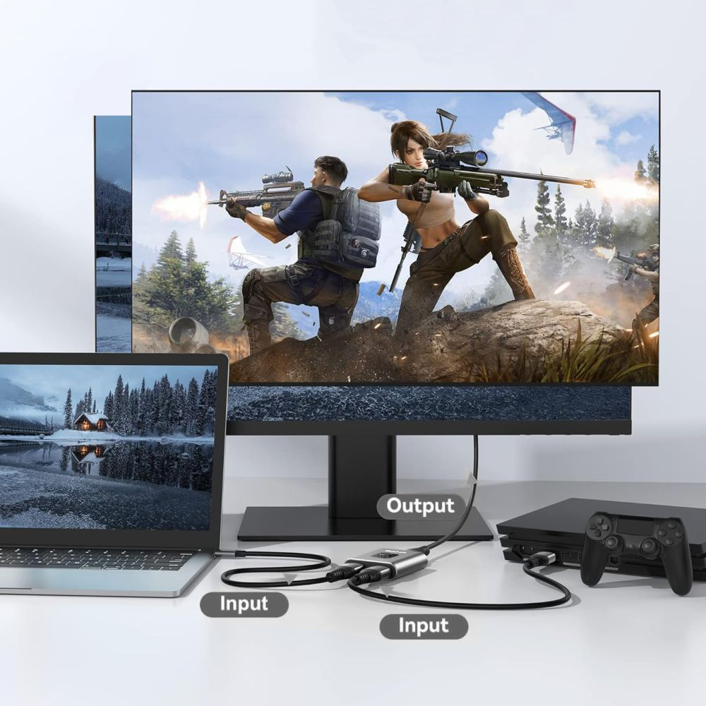 Een monitor toont een videogame. Een laptop, een gameconsole en een adapter zijn aangesloten. De scène bevindt zich op een wit oppervlak.