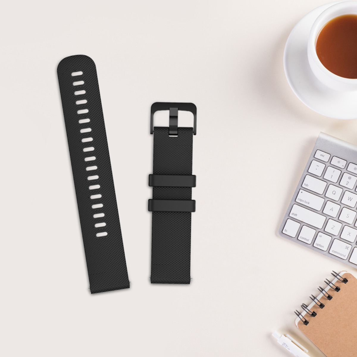 Czarne paski do zegarków, filiżanka kawy, klawiatura, notatnik i długopis na białej powierzchni. Widok z góry, dobrze oświetlone.