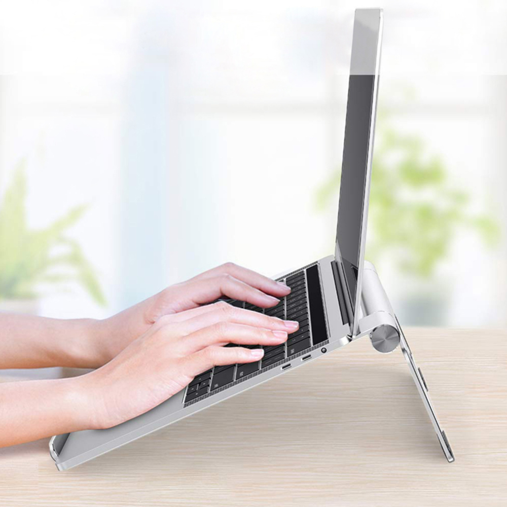 Ręce piszące na srebrnym laptopie na drewnianym stole. Ekran jest podniesiony. Tło jest rozmyte.