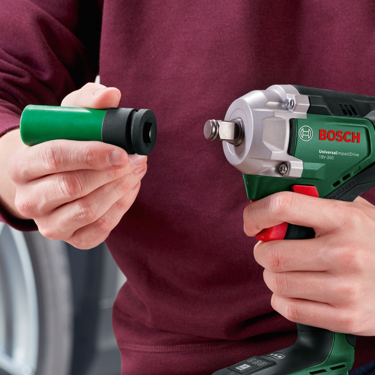 Eine Person hält einen grünen Steckschlüssel und ein Bosch-Elektrowerkzeug. Sie sind dabei, die beiden Werkzeuge zu verbinden.