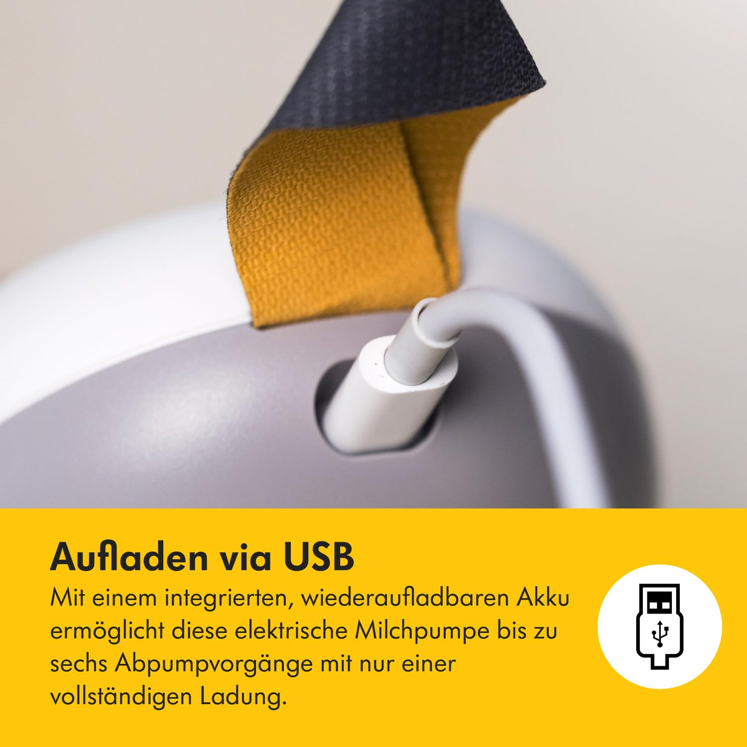 Nahaufnahme eines weißen USB-Kabels, das in ein Gerät eingesteckt ist. Oben ein gelber Riemen mit schwarzem Griff. Text: USB-Aufladung.