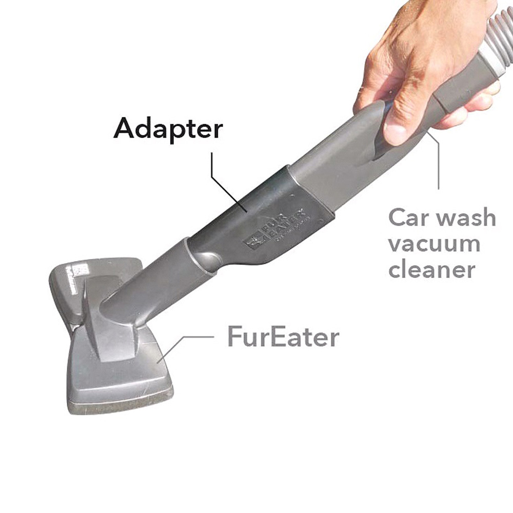 Eine Hand hält einen grauen Autowasch-Staubsauger. Beschriftete Teile sind Adapter und FurEater.