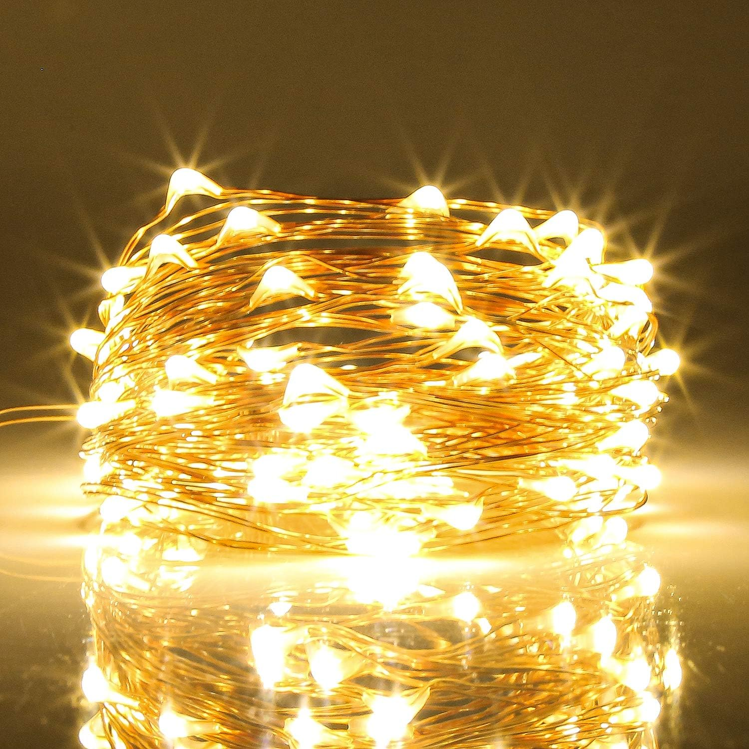 Nahaufnahme einer Spule aus warmweißen Lichterketten mit reflektierender Oberfläche darunter. Die Lichter leuchten hell.