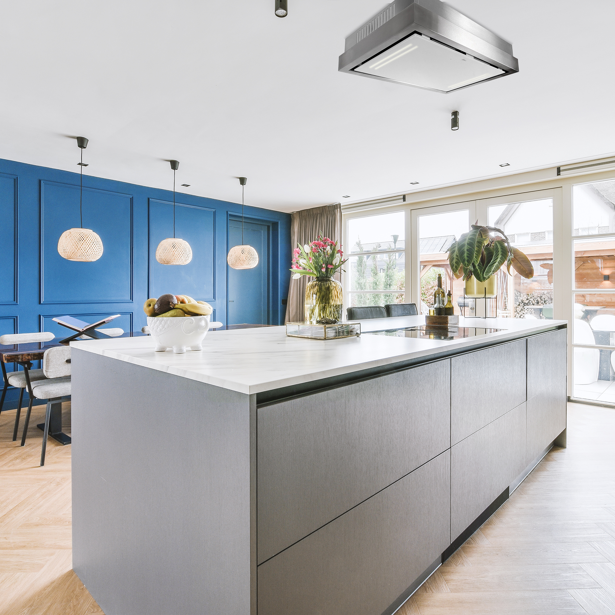 Moderne Küche mit Insel, blauer Wand, Pendelleuchten und großen Fenstern mit Aussicht.