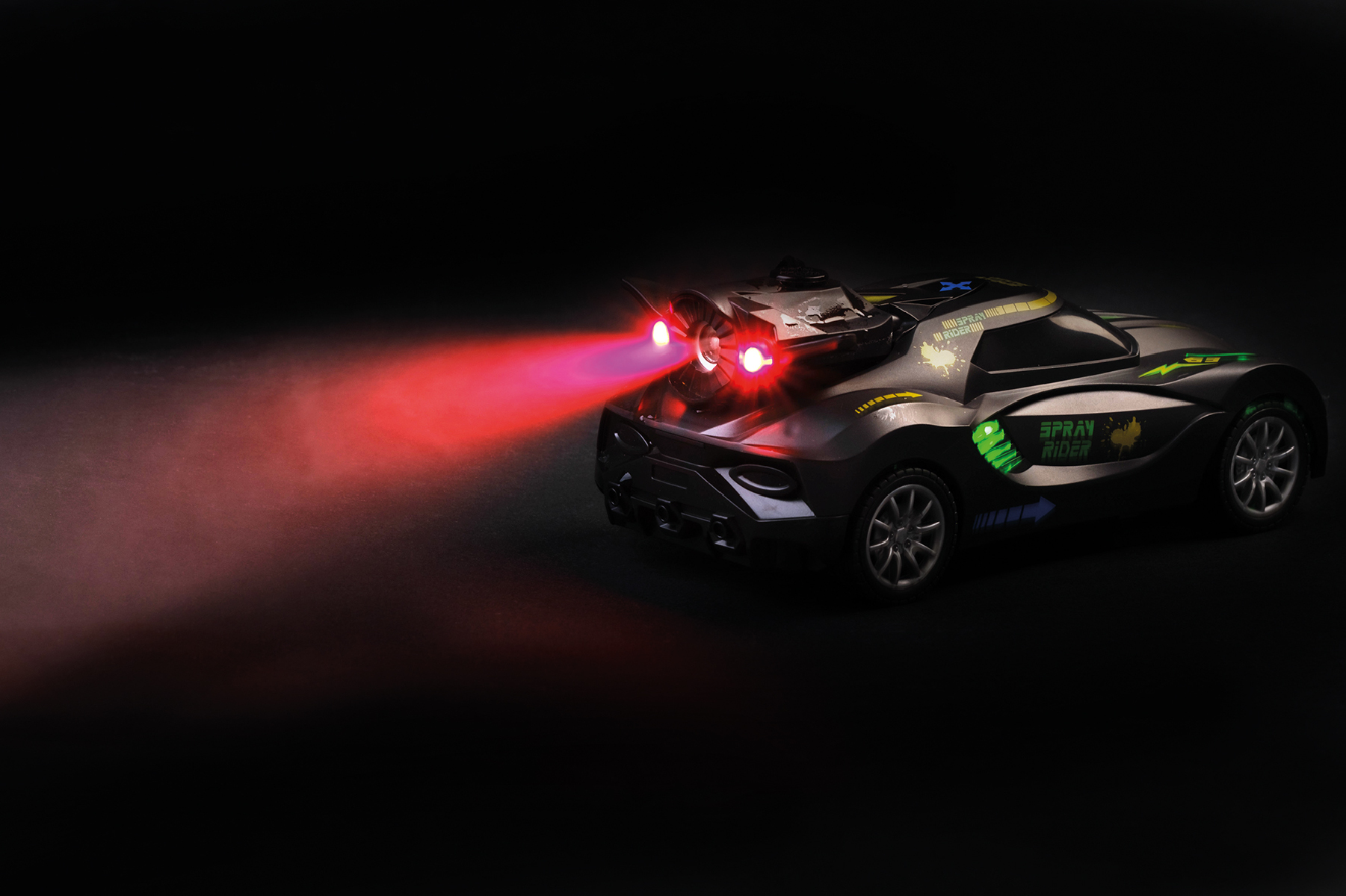 Ein Spielzeugauto mit roten Lichtern auf schwarzem Untergrund. Das Auto hat grüne und gelbe Akzente. Ein roter Lichtstrahl scheint.