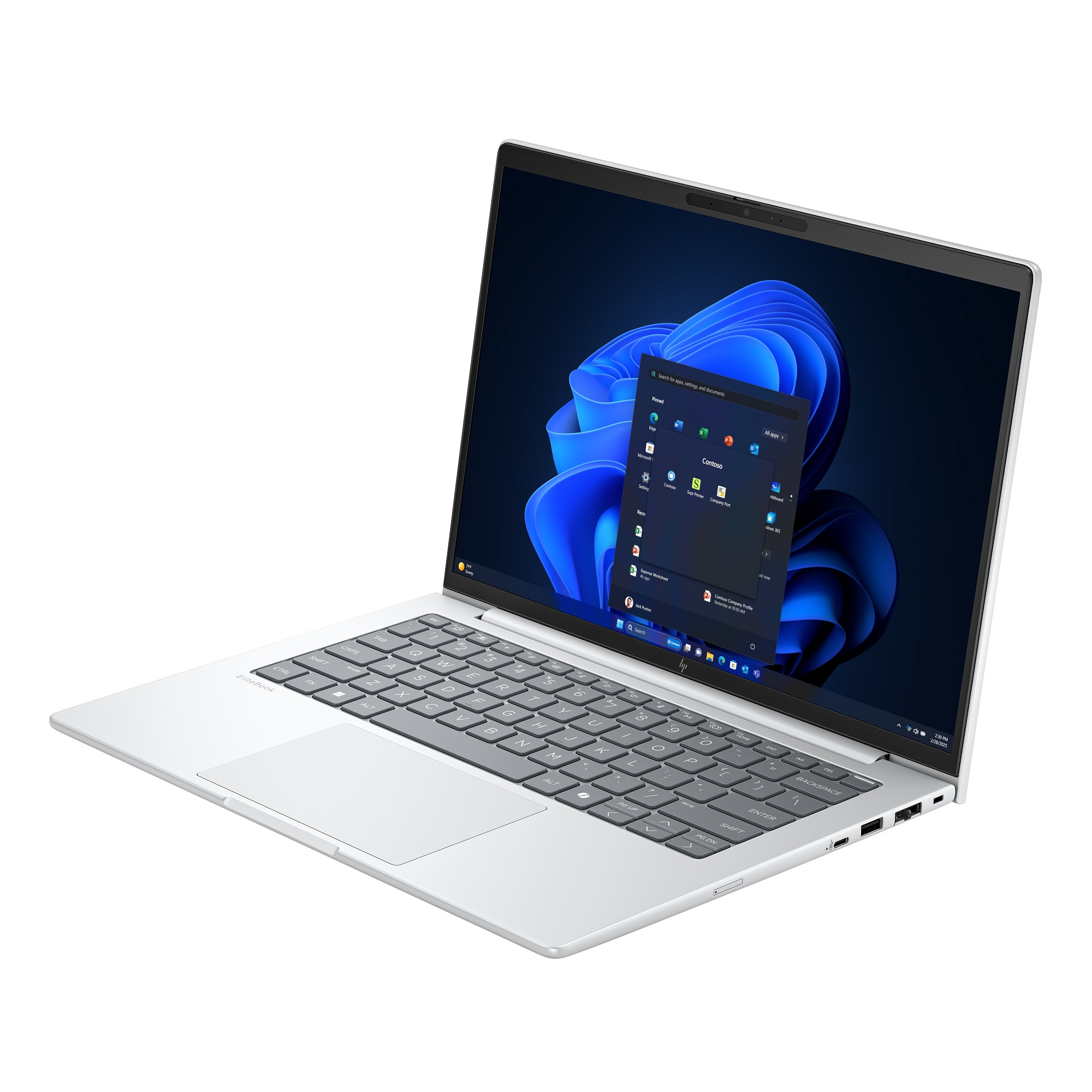 Laptop plateado abierto, interfaz de Windows 11 visible. Teclado y panel táctil en foco. La pantalla muestra iconos de aplicaciones.