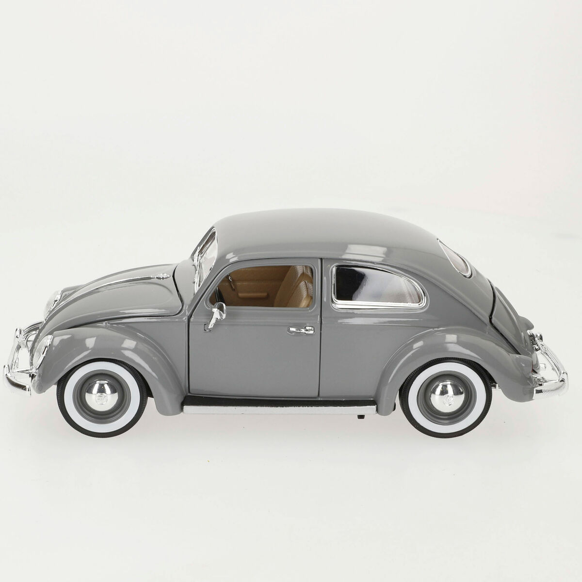 Ein graues Modellauto, ein VW Käfer, steht auf einer weißen Oberfläche. Es hat weiße Reifen und eine beige Innenausstattung.