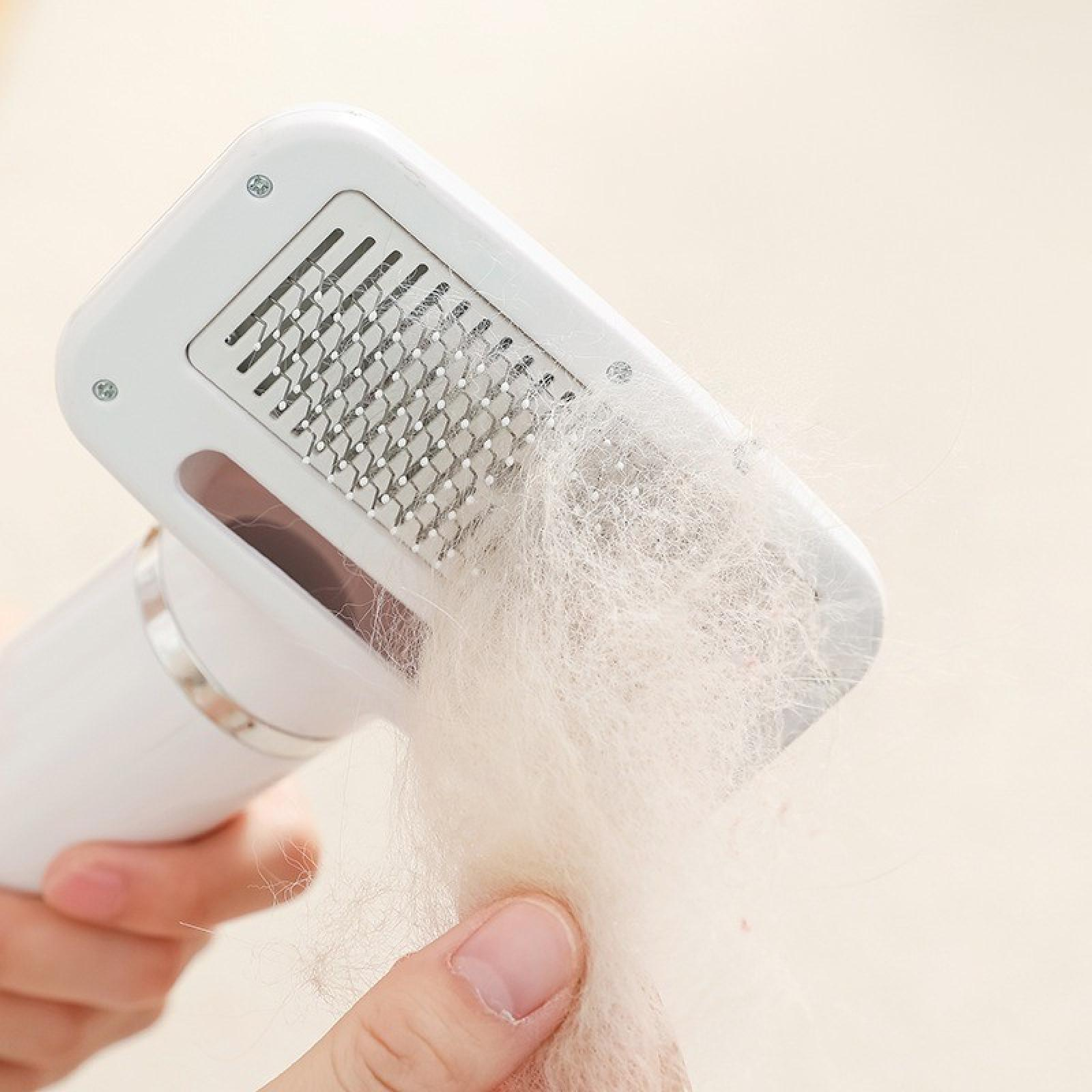 Ein weißes Werkzeug zur Fellpflege mit gesammeltem Fell. Das Werkzeug wird von einer Hand vor cremefarbenem Hintergrund gehalten.