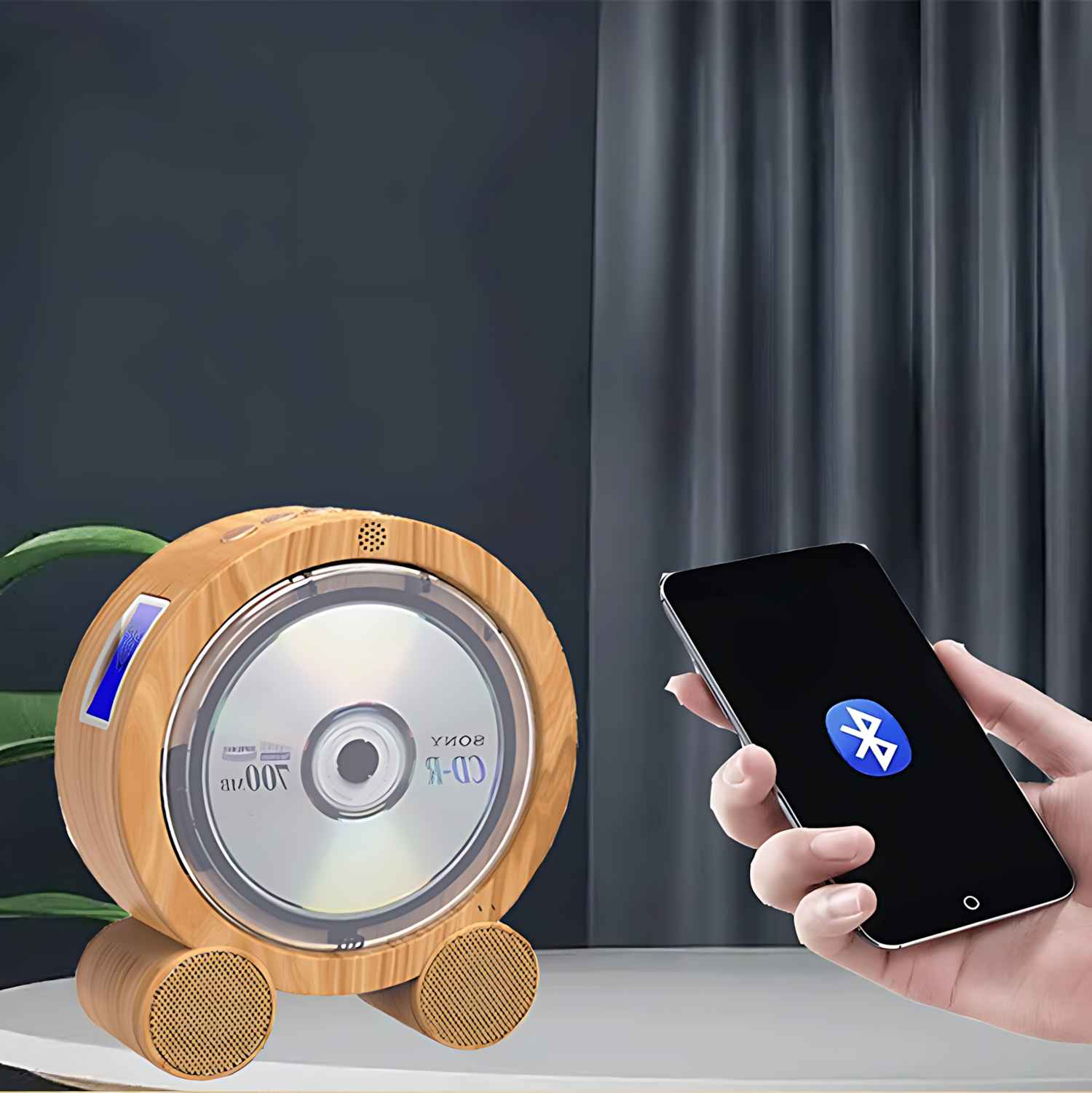 Ein hölzerner CD-Player mit einer CD darin und ein Telefon, das ein Bluetooth-Symbol anzeigt, beides auf einem Tisch. Im Hintergrund ein Vorhang.