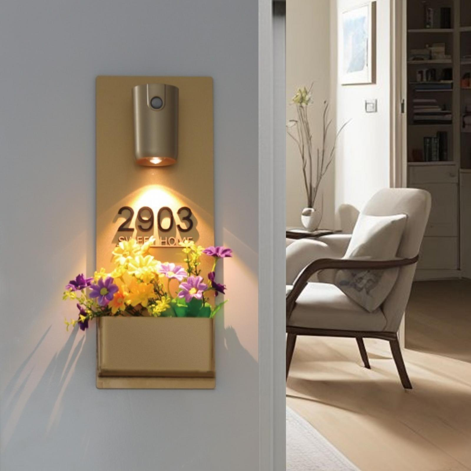 Ein Hotelzimmer-Nummernschild mit Blumen. Ein Stuhl und ein Blick in den Raum sind sichtbar.