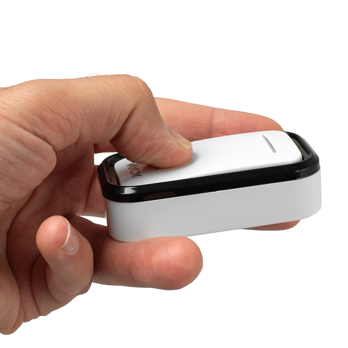 Dłoń trzyma biało-czarne urządzenie. Urządzenie ma przycisk, który jest wcisnięty przez palec wskazujący.