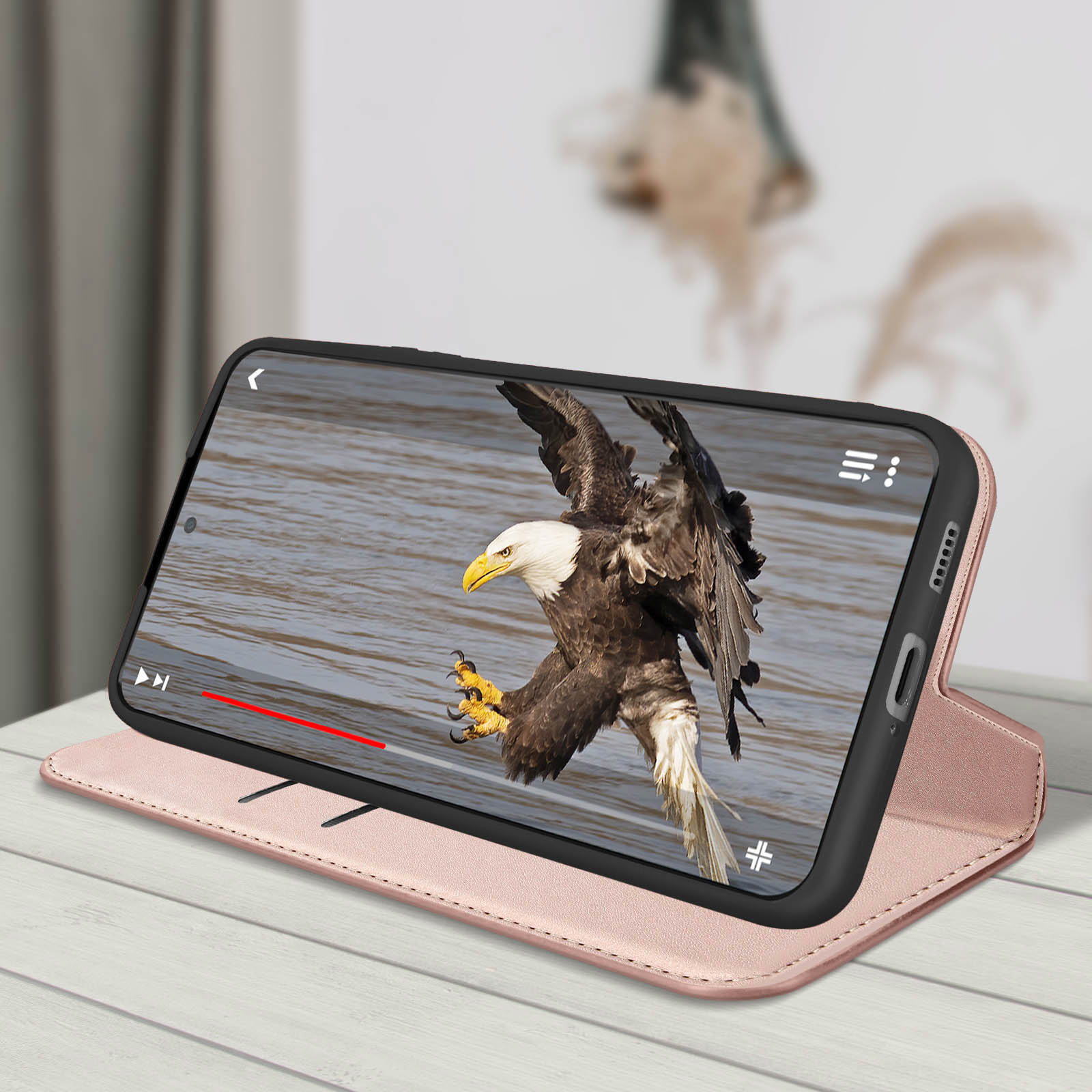 Un téléphone affiche un aigle en vol au-dessus de l'eau. Le téléphone est dans un étui rose, sur une table en bois.