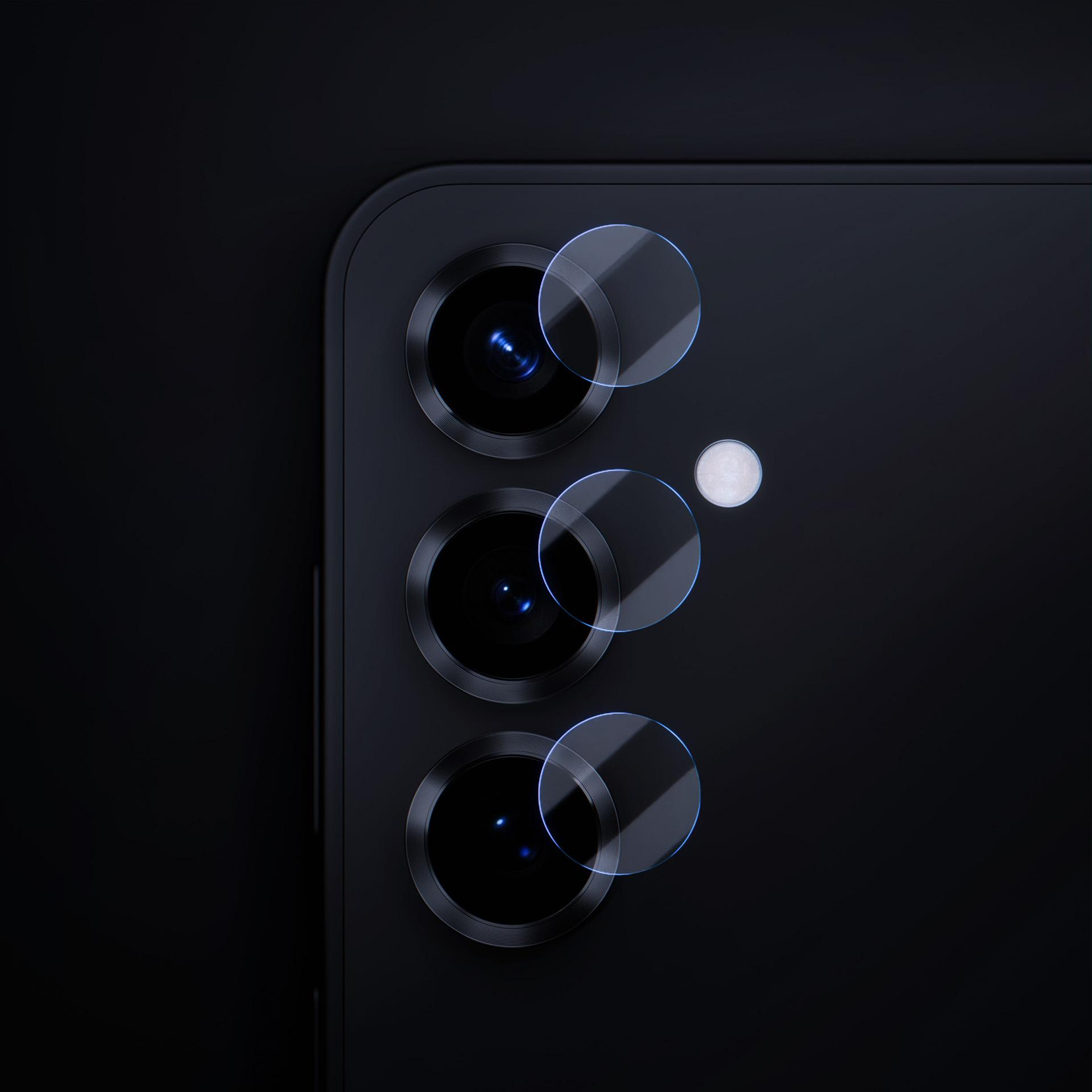 Zbliżenie na układ kamer w telefonie. Widoczne trzy obiektywy z osłonami. Tło jest czarne.