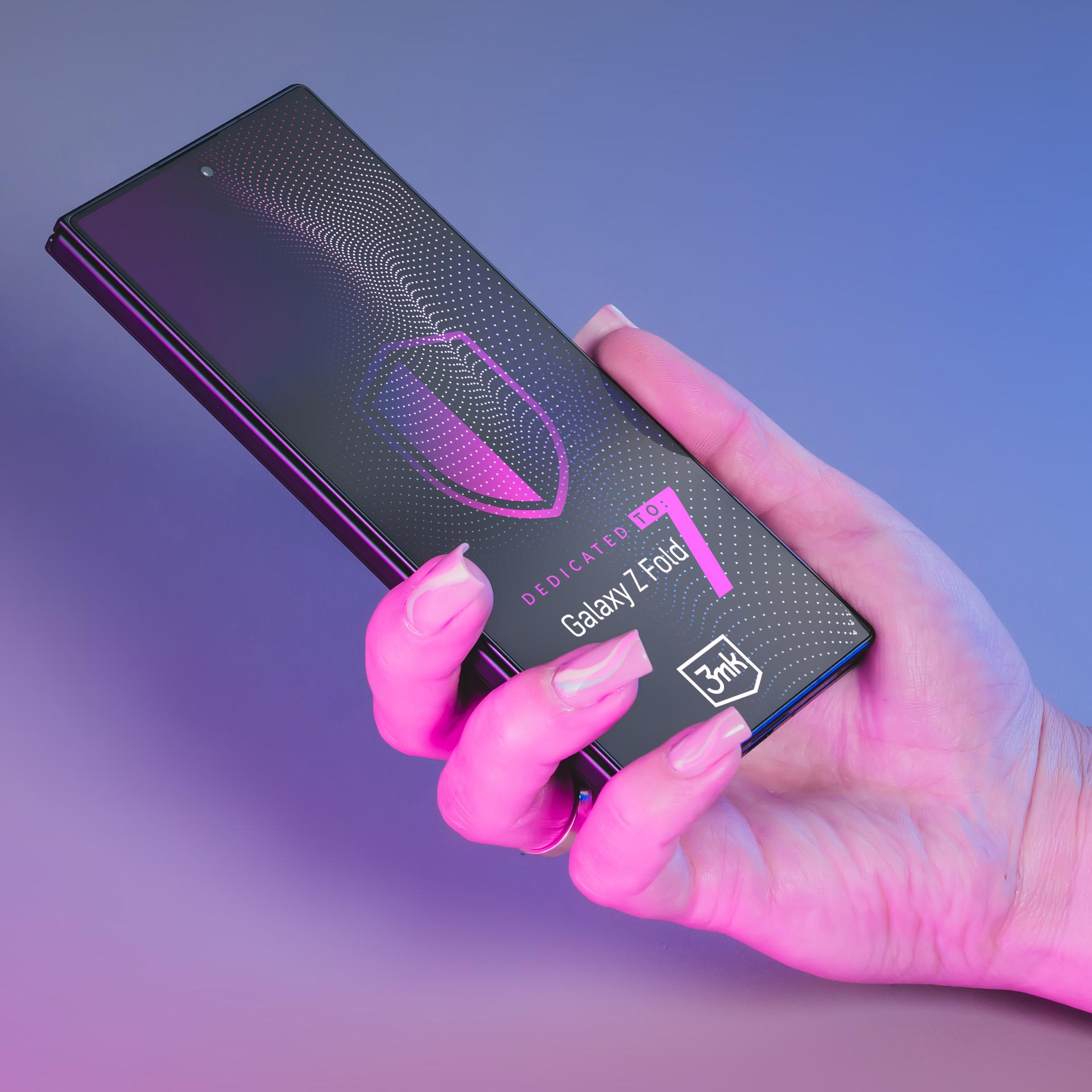 Una mano tiene un telefono con un design rosa che dice 'Dedicated to Galaxy Z Fold'. Lo sfondo è viola e blu.