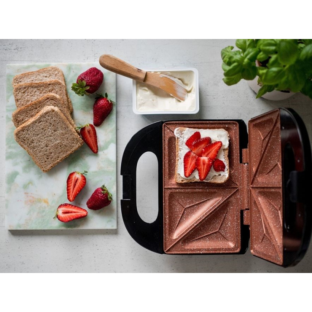 Toster z kanapką z truskawkami. Kromki chleba, truskawki, masło i roślina w tle.