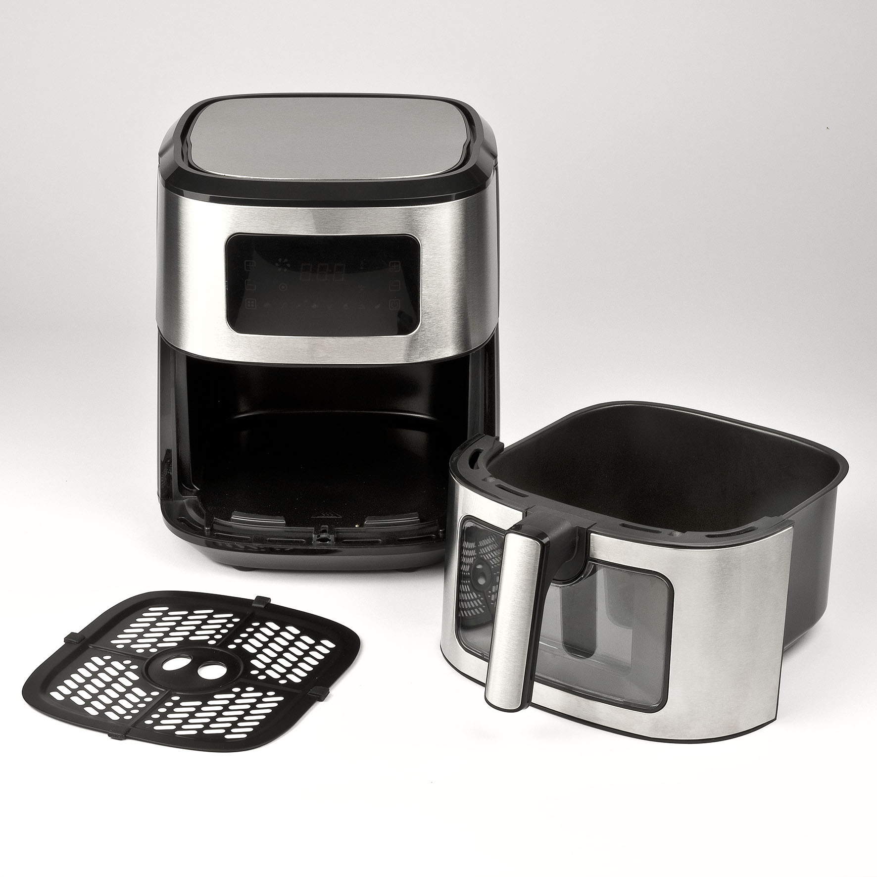 Frytkownica beztłuszczowa, zdemontowana, na białej powierzchni. Części: jednostka główna, kosz, perforowana płyta.